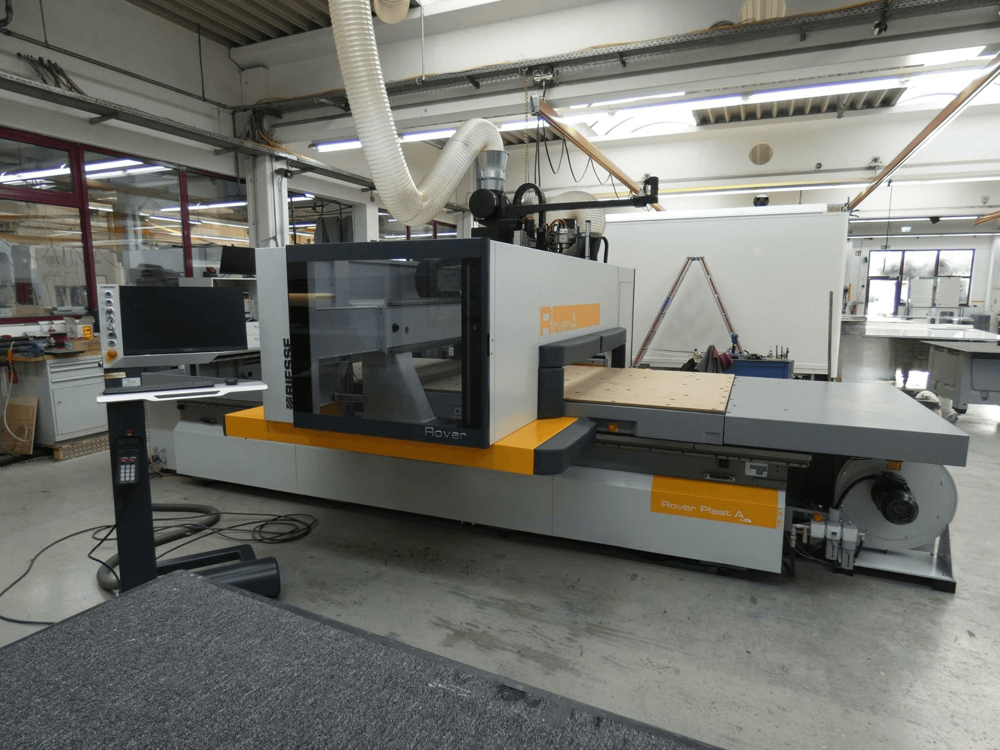 Vista frontal do centro de maquinagem de madeira BIESSE ROVER PLAST A FT 1224 CNC, com o monitor e o painel de controlo visíveis.