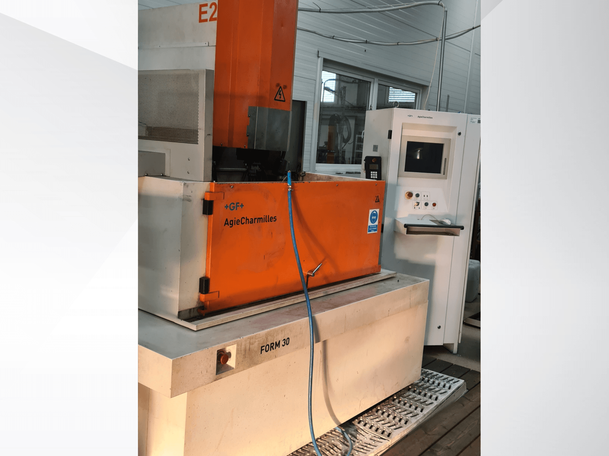 Máquina de eletroerosão por penetração AgieCharmilles FORM 30, vista frontal, com o armário de comando laranja e a mangueira de água visíveis.