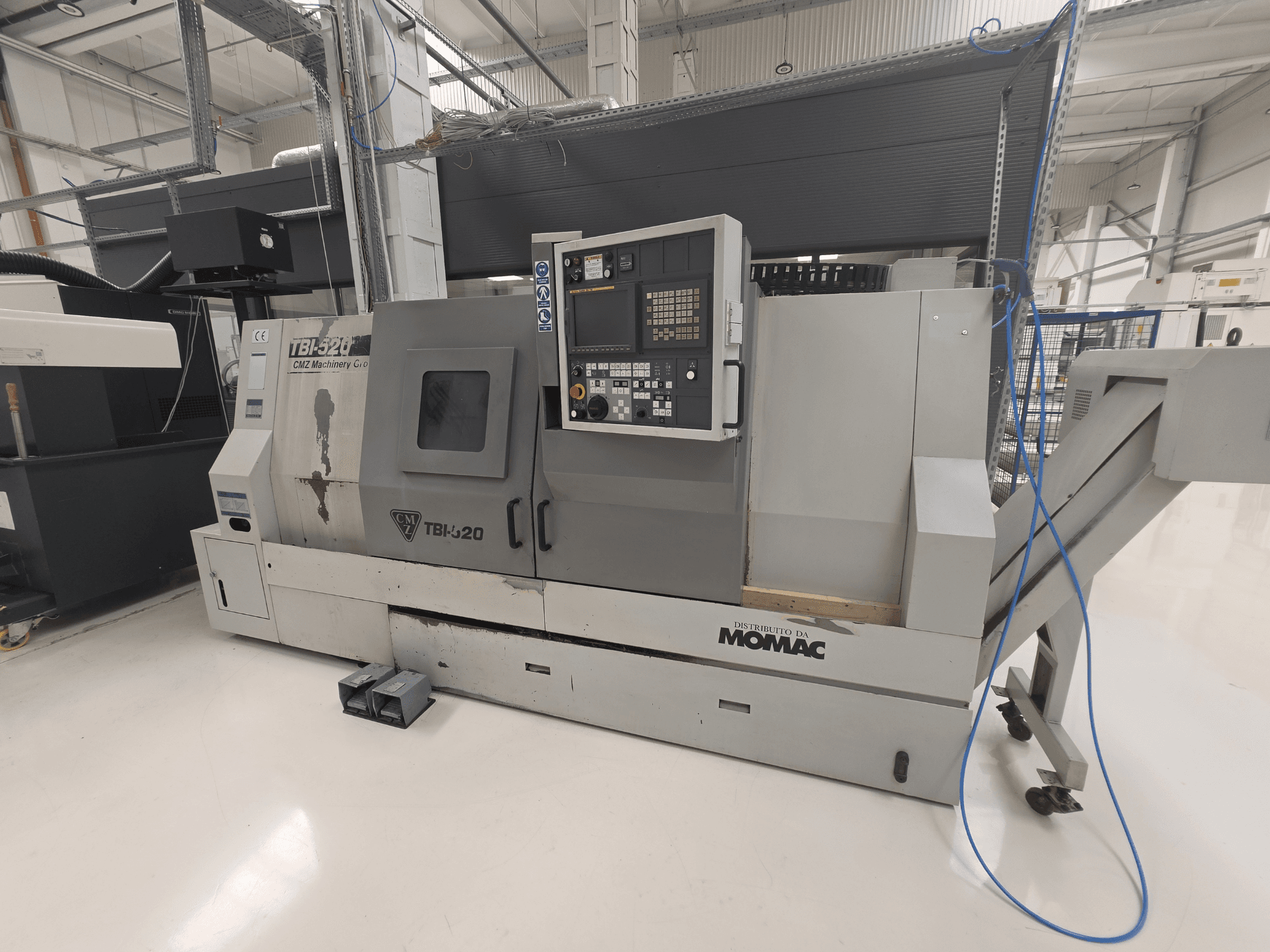 Torno horizontal CMZ TBI-520, vista lateral, mostrando o painel de controlo e detalhes da máquina num ambiente industrial organizado.