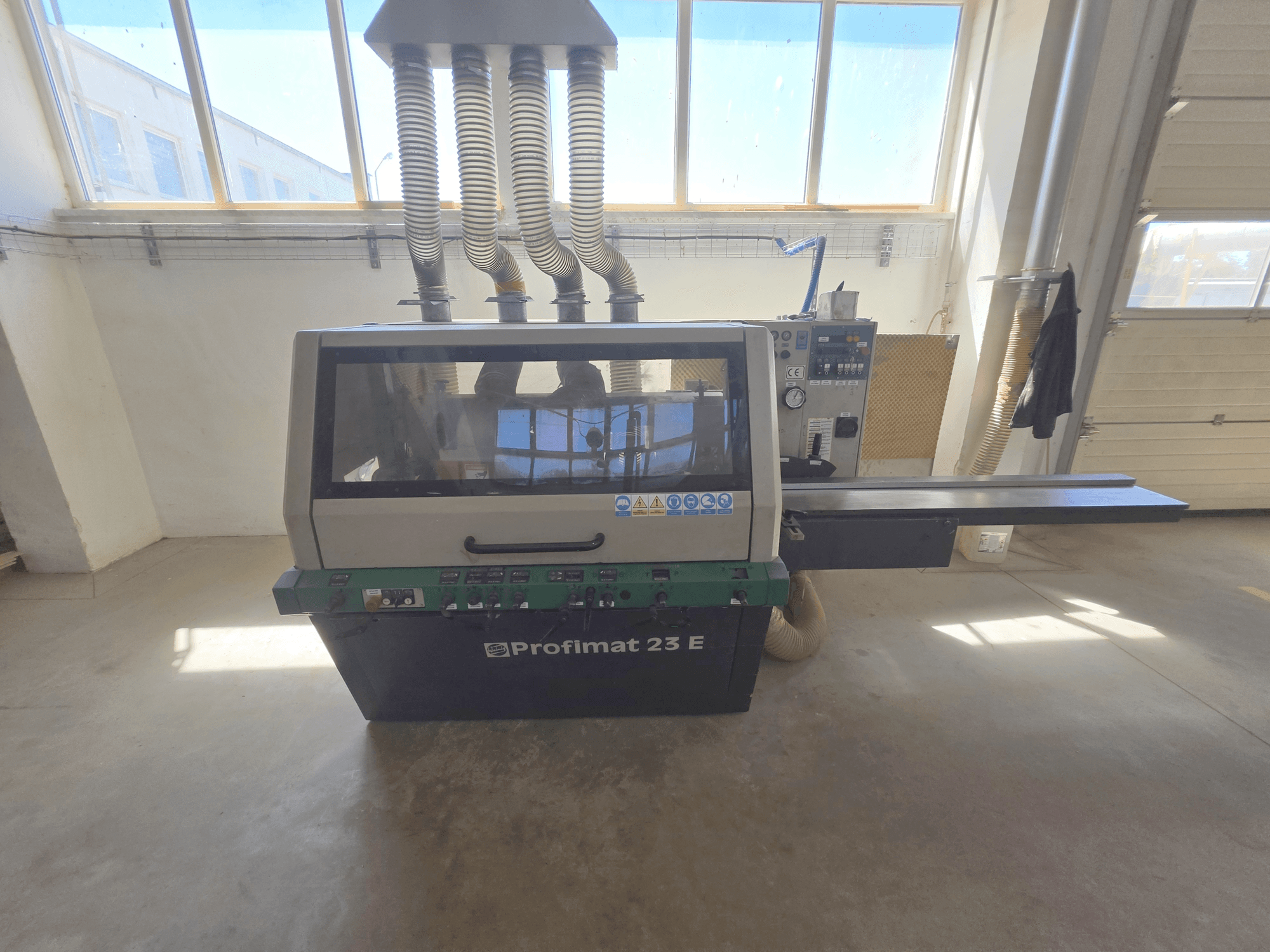 Plaina para madeira WEINIG DIMTER PROFIMAT 23 E, vista frontal, com painel de controlo, mesa de alimentação e mangueiras de extração de pó.
