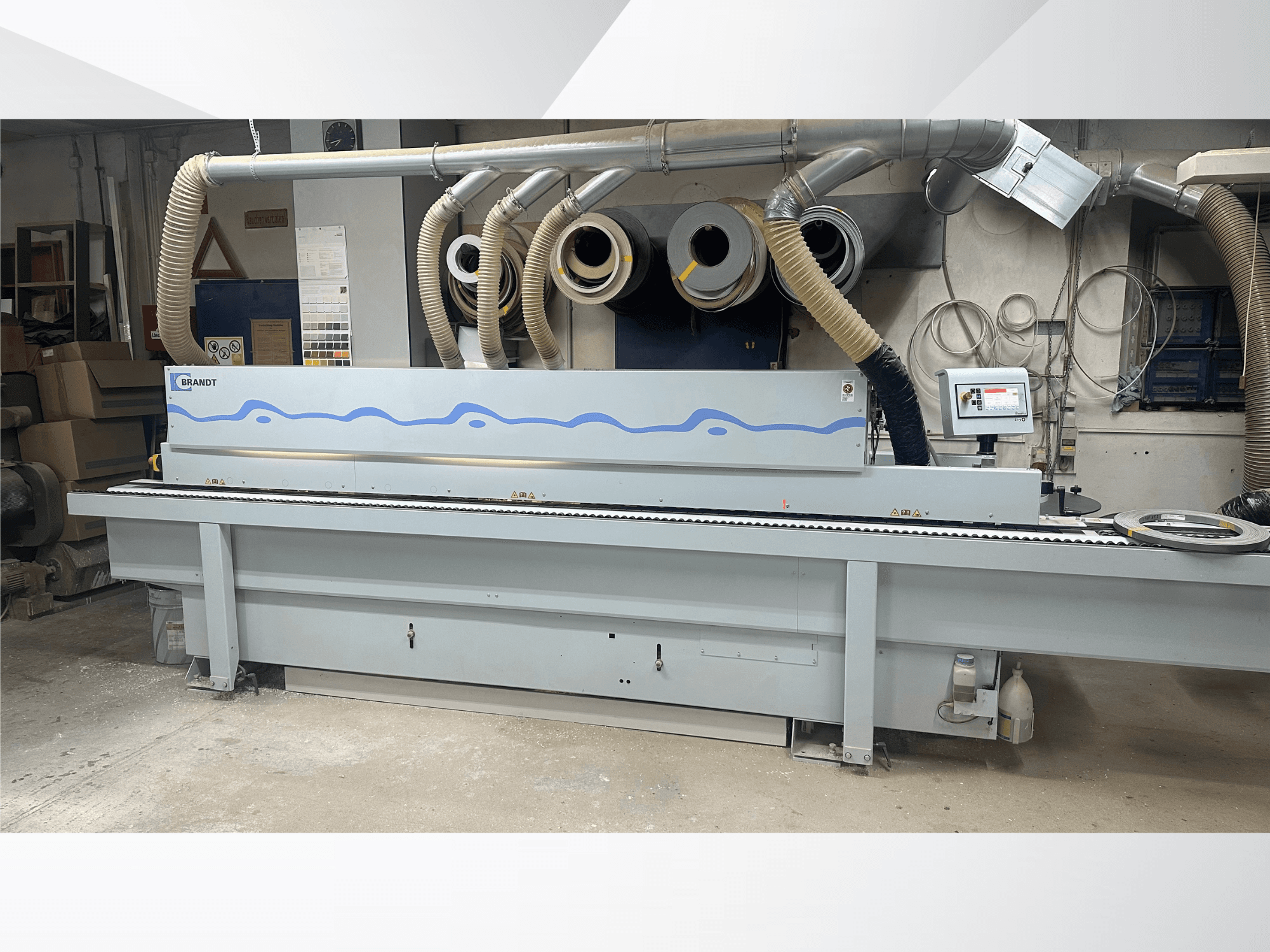 Máquina de colar bordas HOMAG KDF 230 numa oficina, mostrando a vista frontal, o painel de controlo e o sistema de extração de poeira.