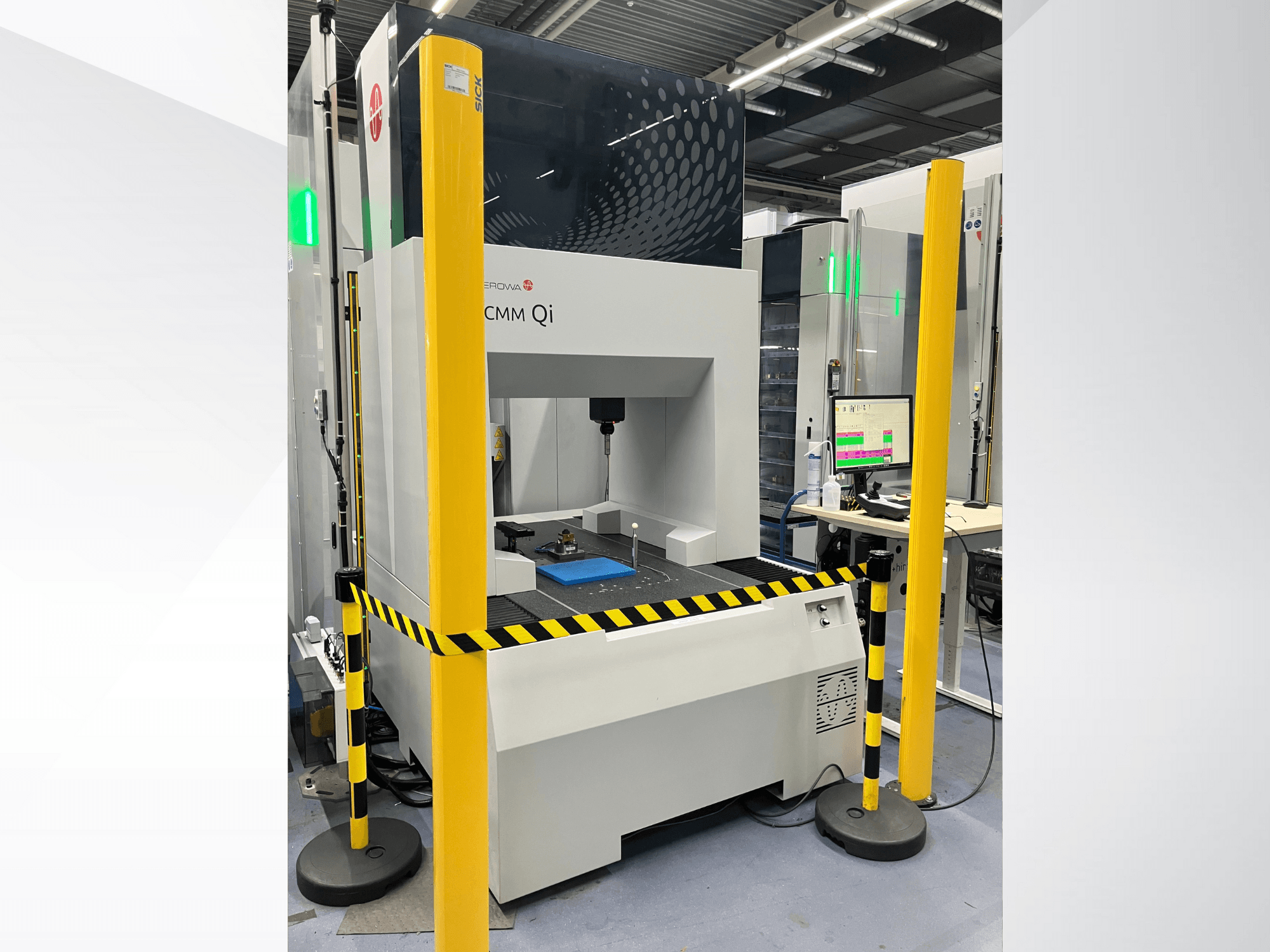 Máquina de medição por coordenadas CMM Qi da Aerovent, vista frontal com barreiras de segurança e monitor que apresenta os dados de medição.