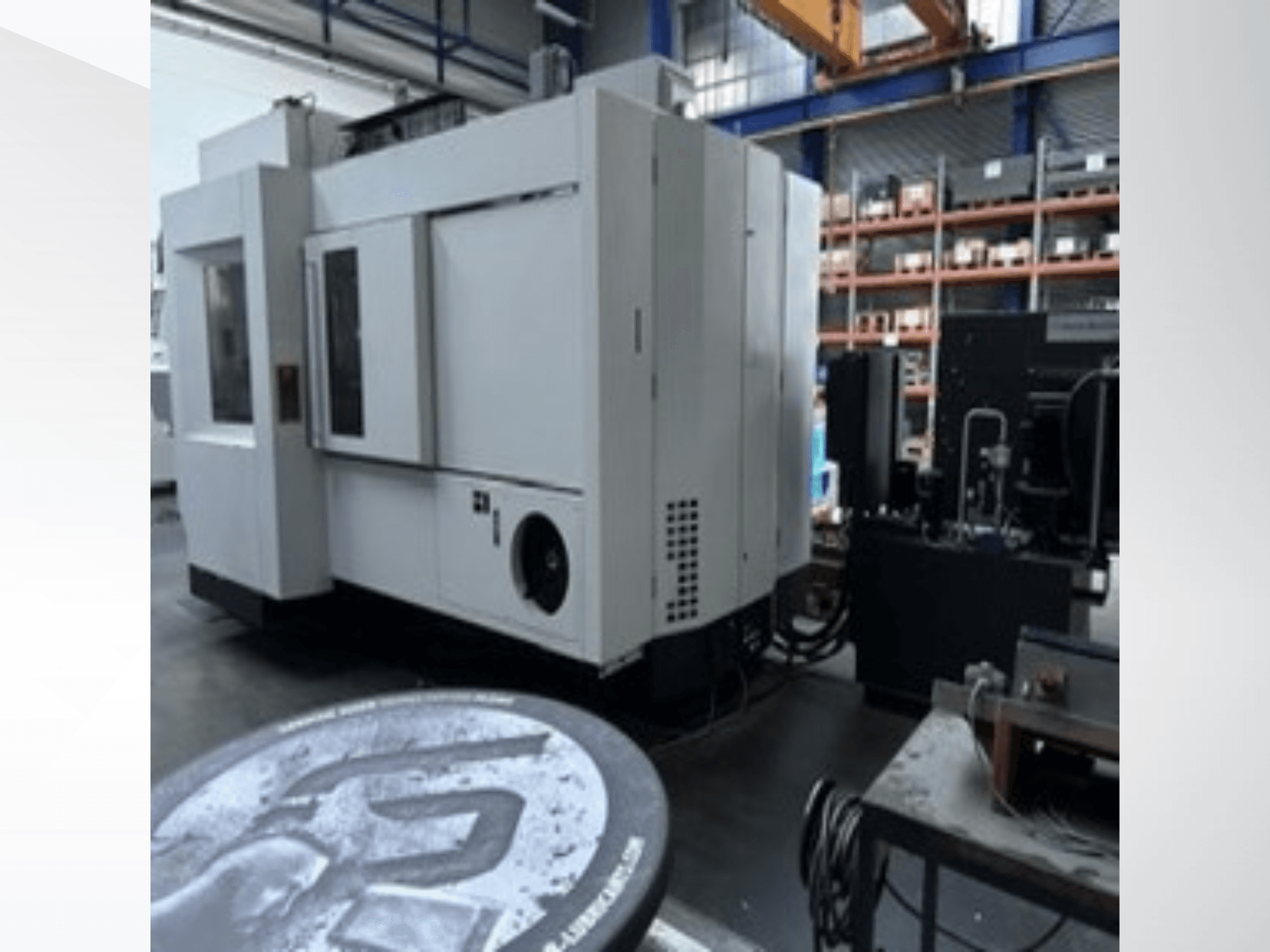 Centro de maquinagem universal MIKRON HPM 1350 U branco numa oficina, vista lateral que mostra o grande painel de controlo e o ambiente industrial.