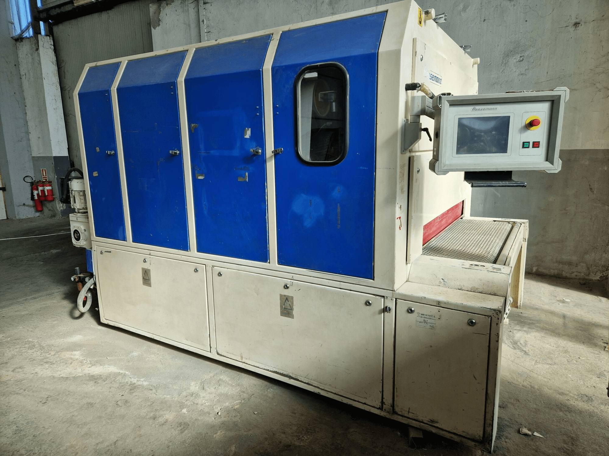 Máquina industrial da marca "Sedecom", vista lateral; apresenta painéis azuis, um ecrã de controlo e uma superfície texturada para manuseamento de produtos.