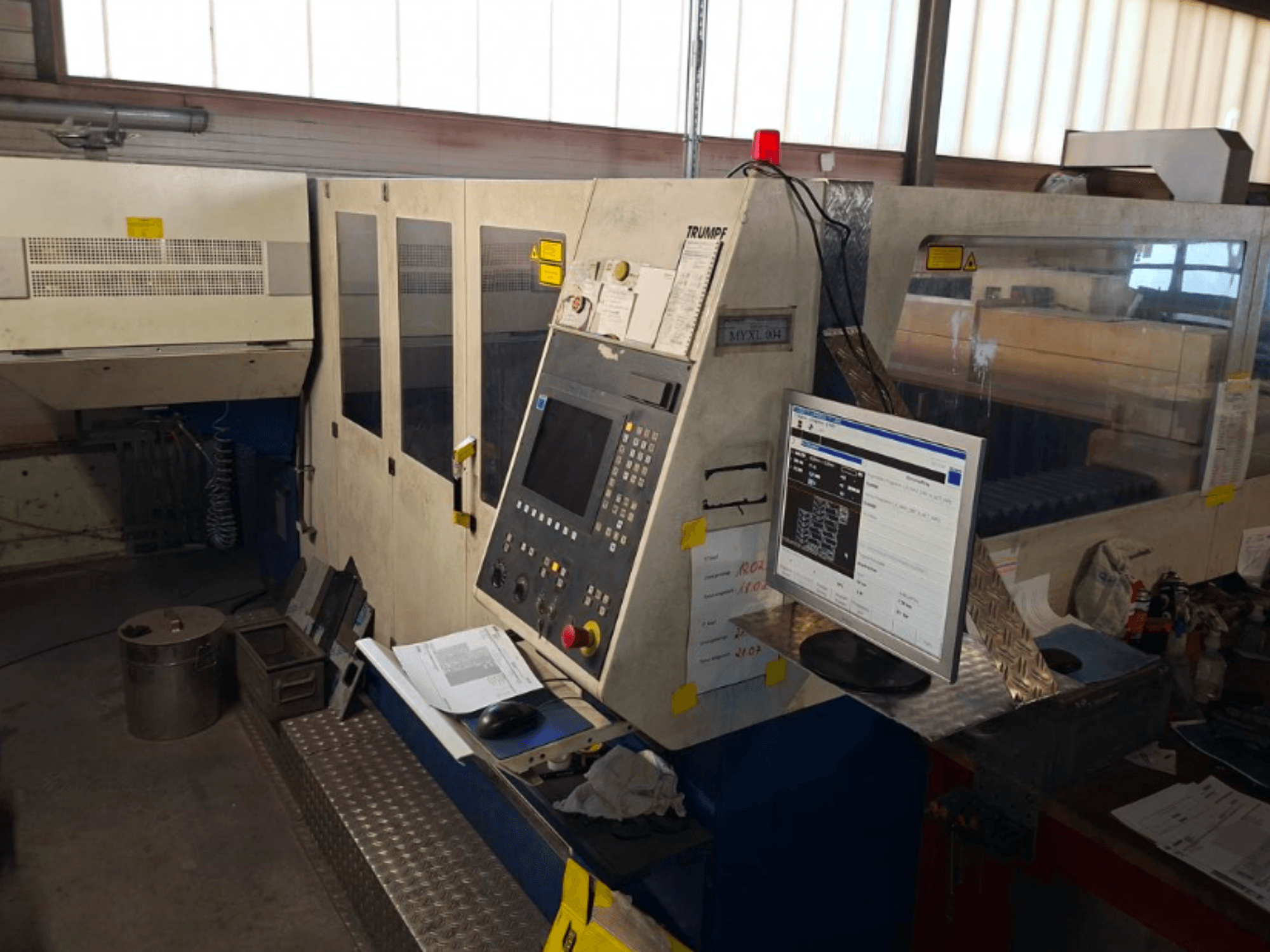 Máquina de corte a laser TRUMPF Trumatic L 4030 CO2, vista frontal mostrando o painel de controlo e o monitor, com detalhes do espaço de trabalho visíveis.