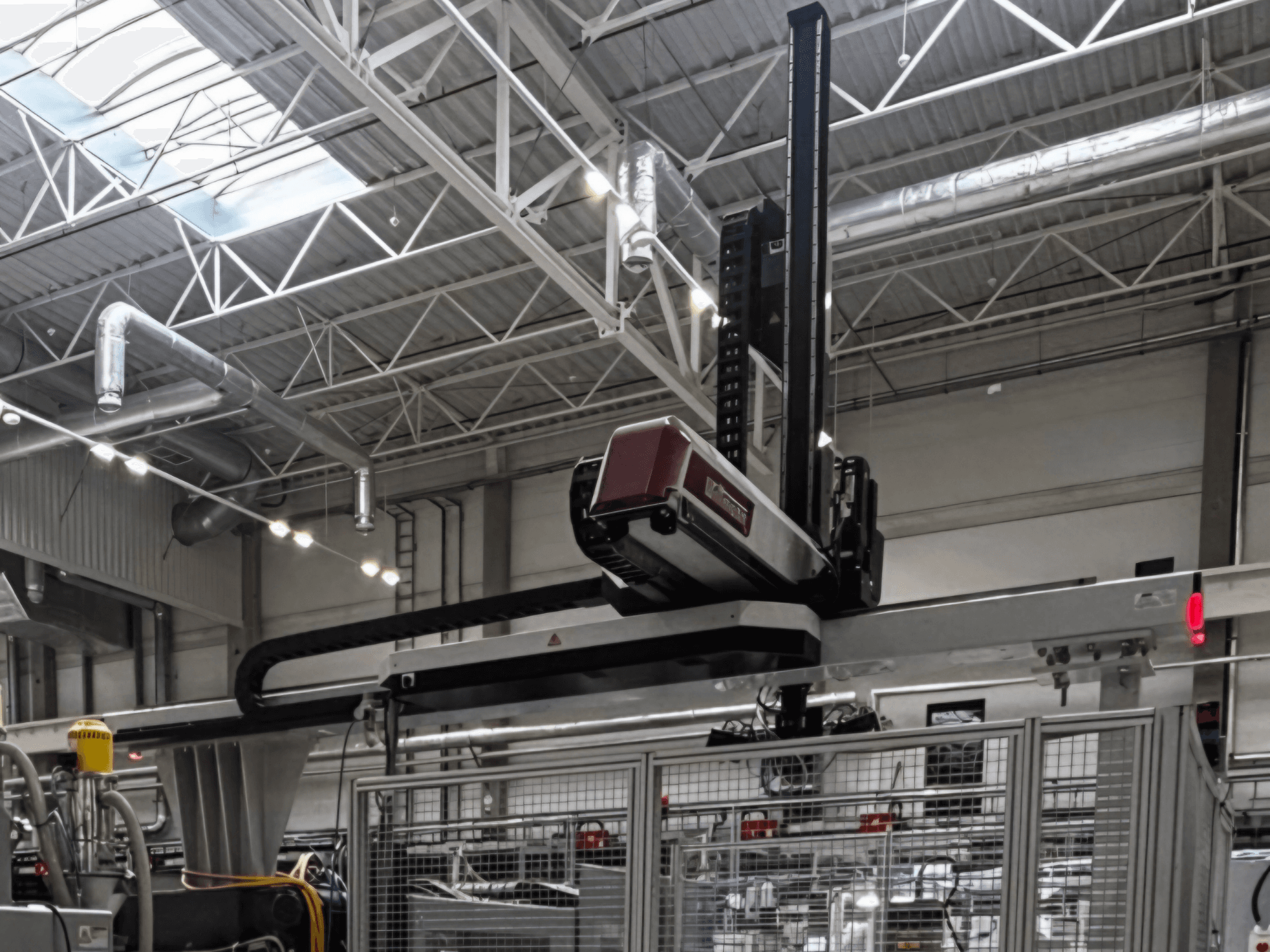 Máquina de processamento de plástico WITTMANN W832PRO num ambiente fabril, vista lateral que mostra o sistema suspenso e o cenário industrial.