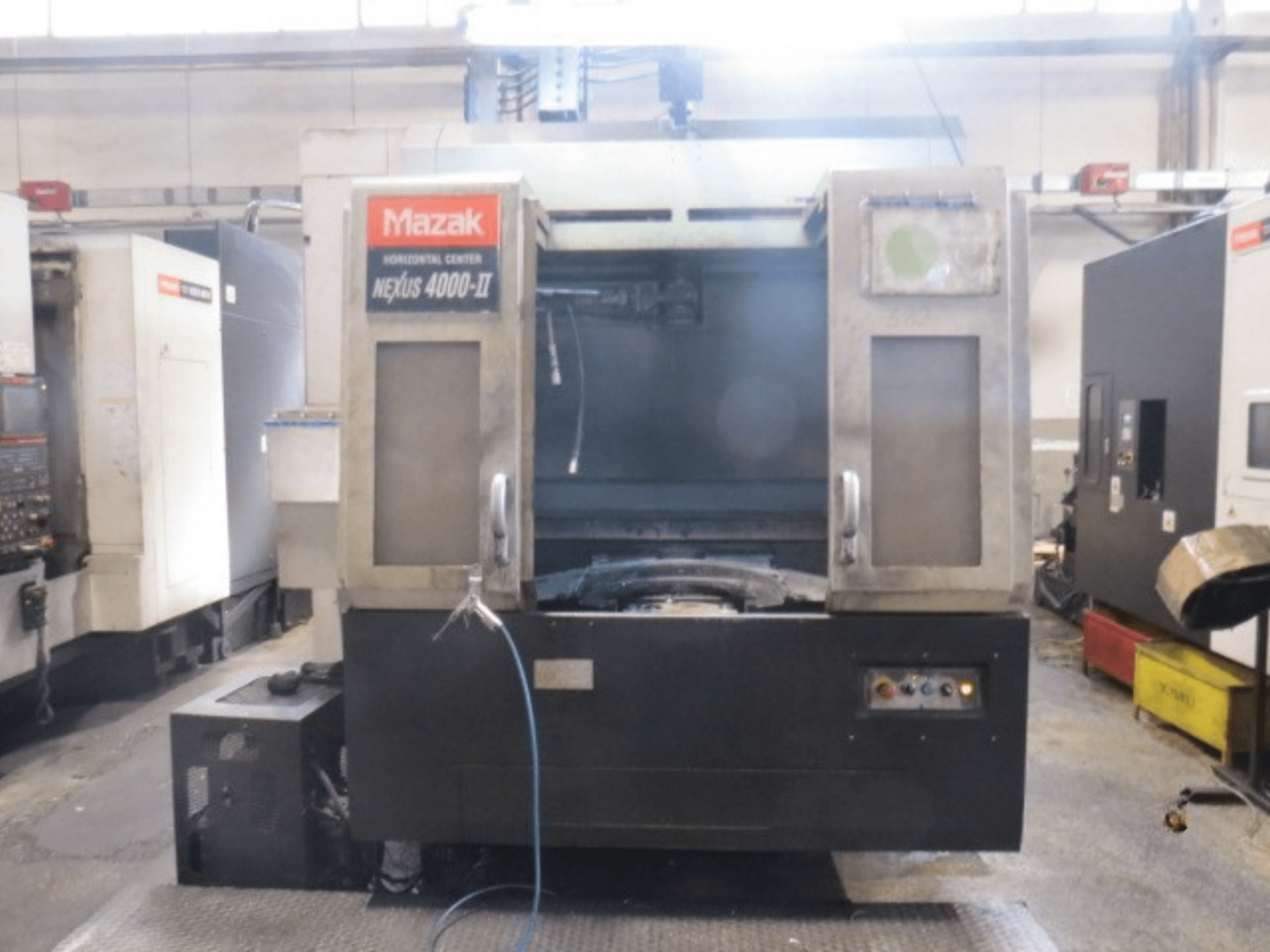 Centro de maquinagem horizontal Mazak NEXUS 4000 II, vista frontal que mostra o painel de controlo, o sistema de alimentação de líquido de arrefecimento e a área de trabalho aberta.