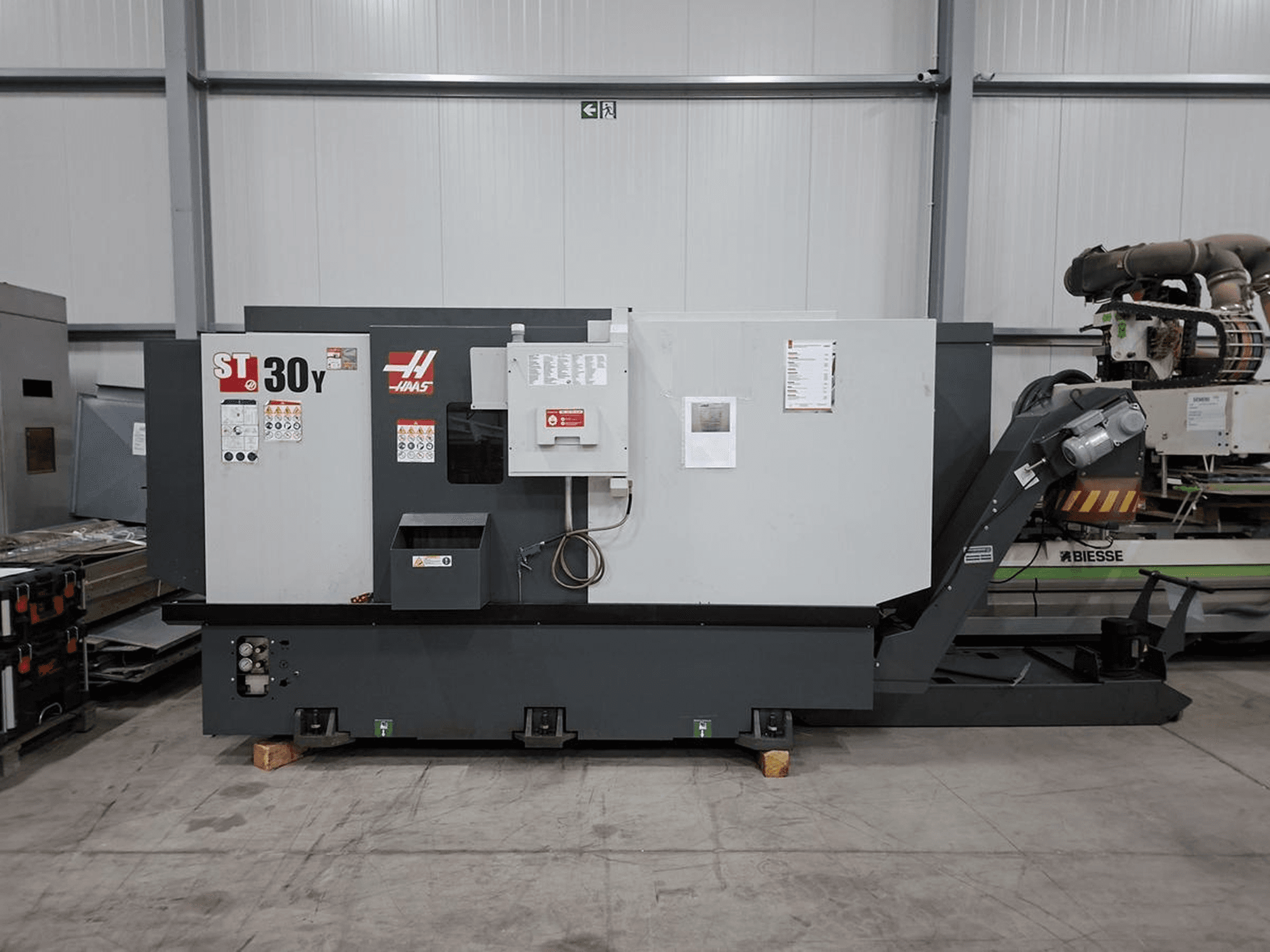 Torno horizontal Haas ST-30Y visto de lado, mostrando os comandos, as etiquetas e a sua construção robusta numa oficina espaçosa.
