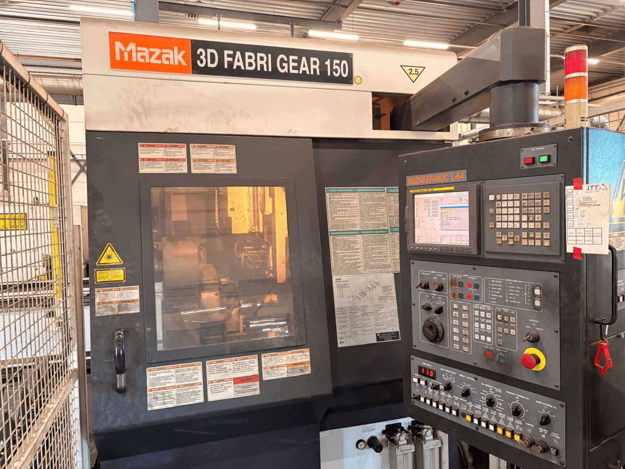 Máquina de corte de tubos Mazak 3D Fabri Gear 150, vista frontal que mostra o painel de controlo, as etiquetas de segurança e a interface operacional.