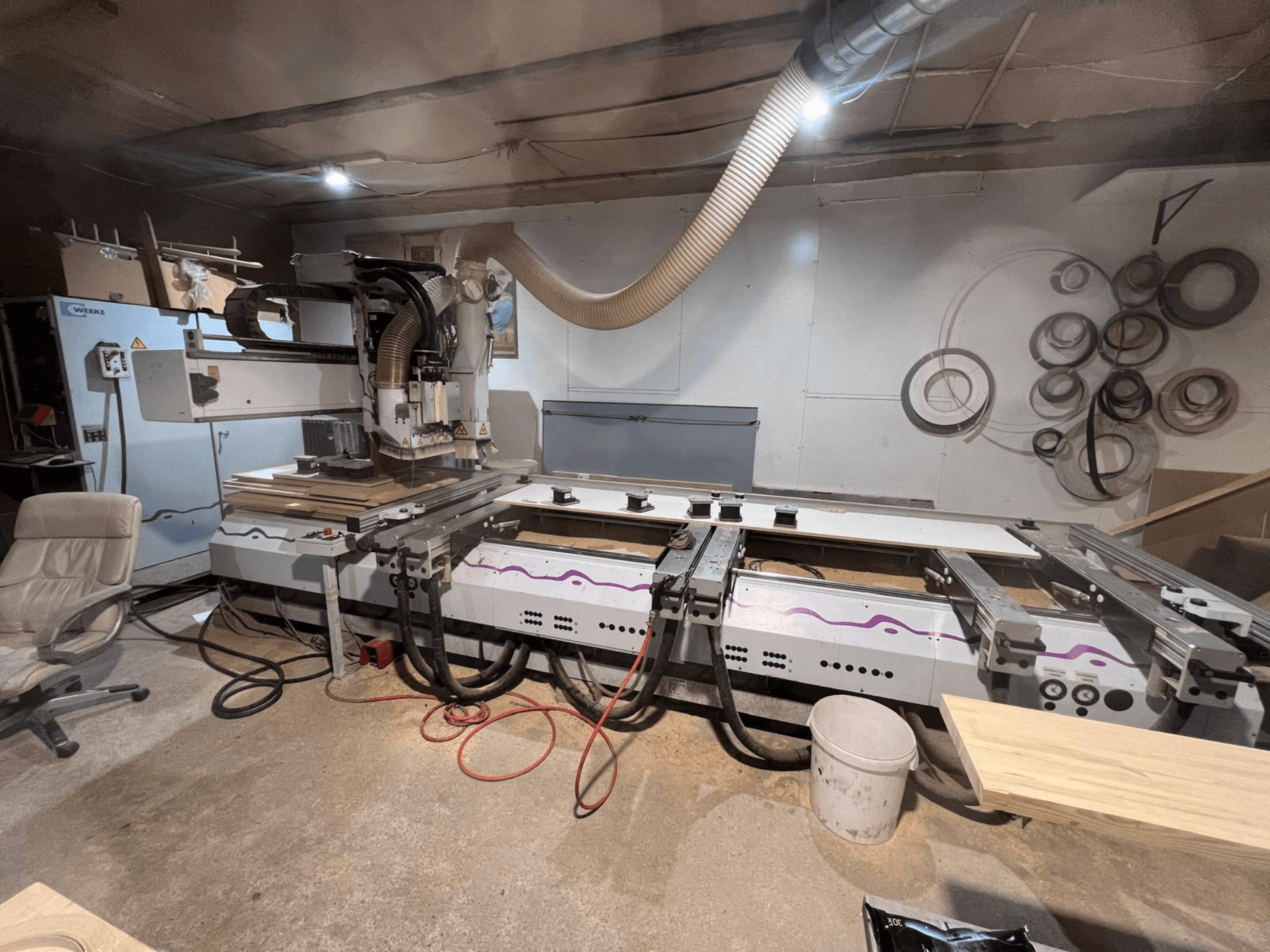 Centro de usinagem de madeira CNC Weeke OPTIMAT BP 120 na oficina, vista frontal com peças de madeira e ferramentas visíveis na superfície.