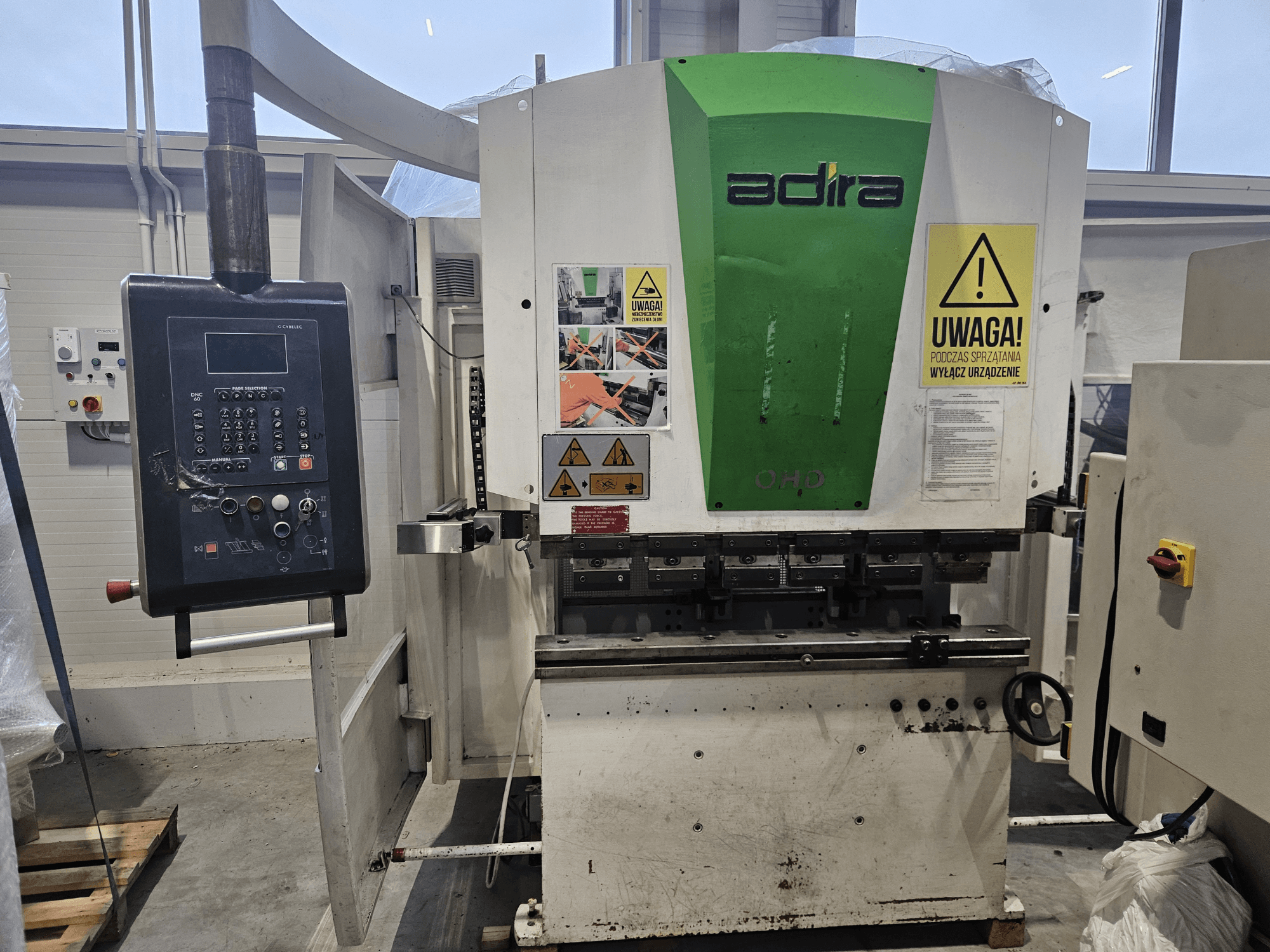 Máquina Adira OHD vista de frente, com um painel de controlo, avisos de segurança e botões de funcionamento.