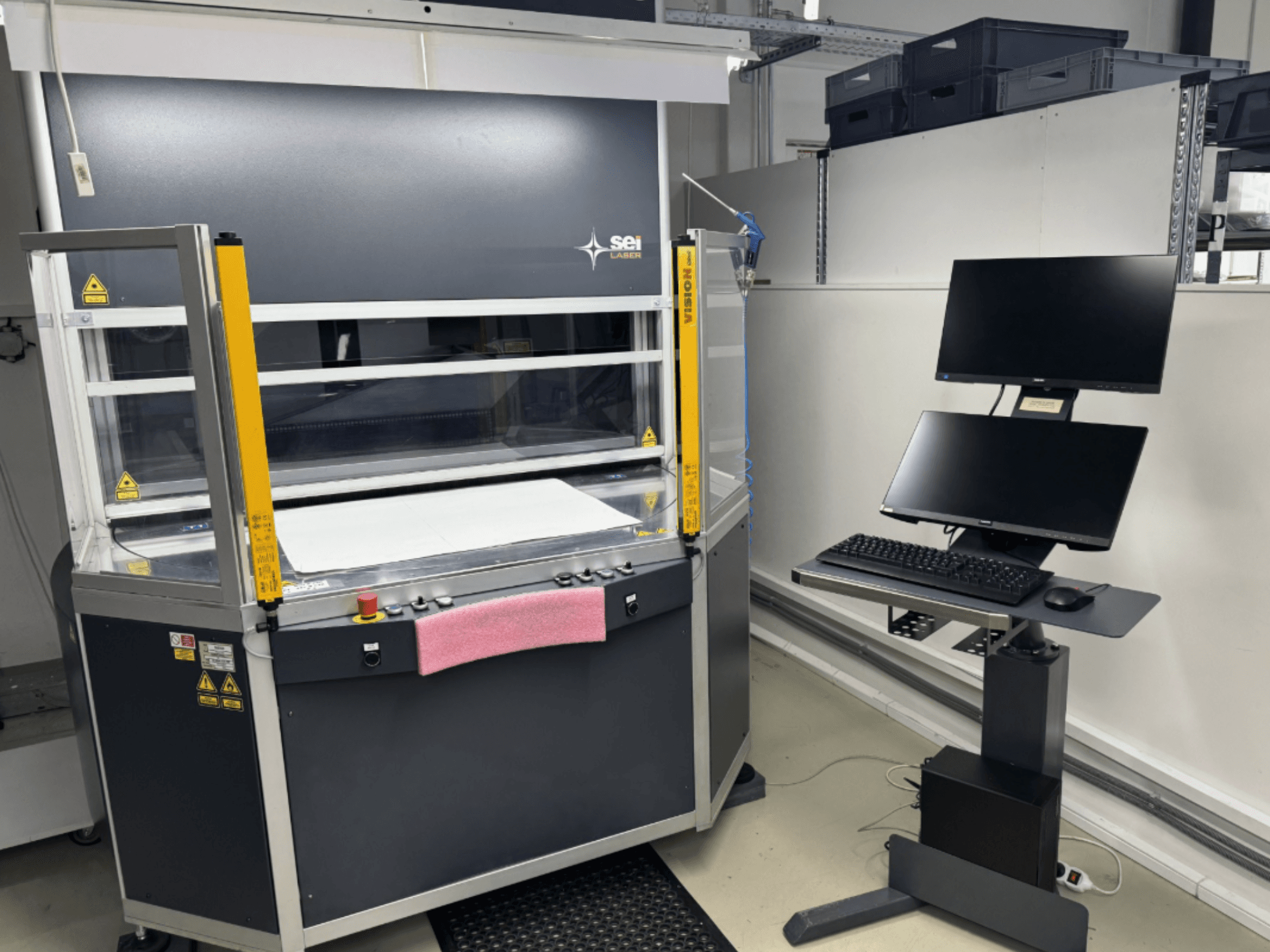 Máquina de corte a laser de CO₂ SEI Laser INFINITY 5070 V300 vista de frente, com painel de controlo e estação de monitorização acoplada.