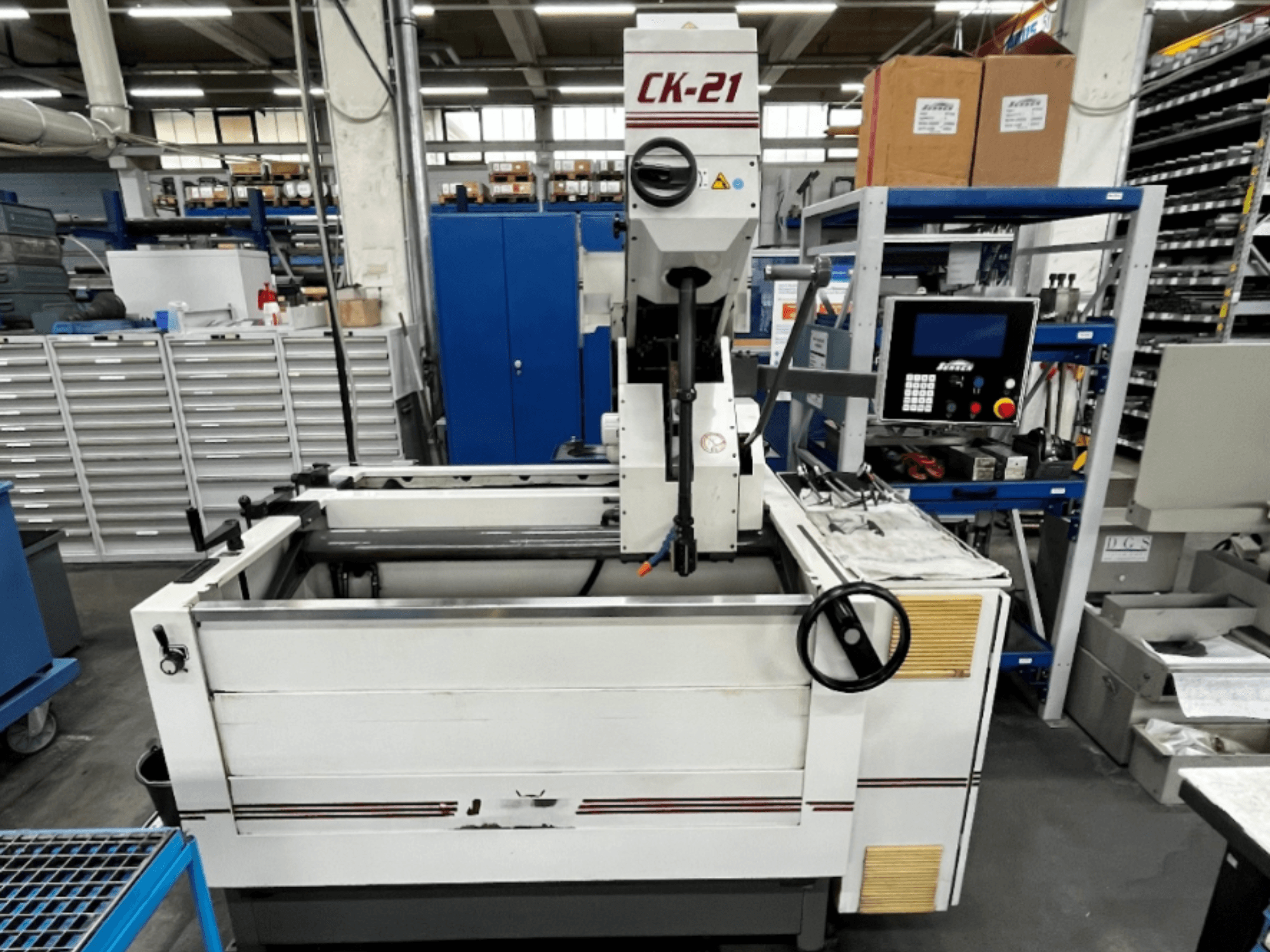 Máquina de afiar vertical Sunnen CK-21-CC em vista frontal, com controlos, área de afiar e equipamento de apoio em segundo plano.