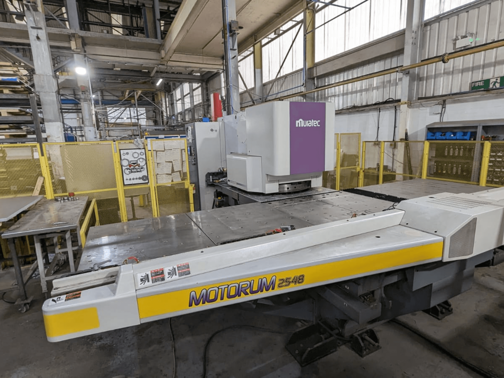 Prensa puncionadora CNC Muratec MOTORUM 2548, vista frontal que mostra o painel de controlo e a mesa de trabalho num ambiente fabril.