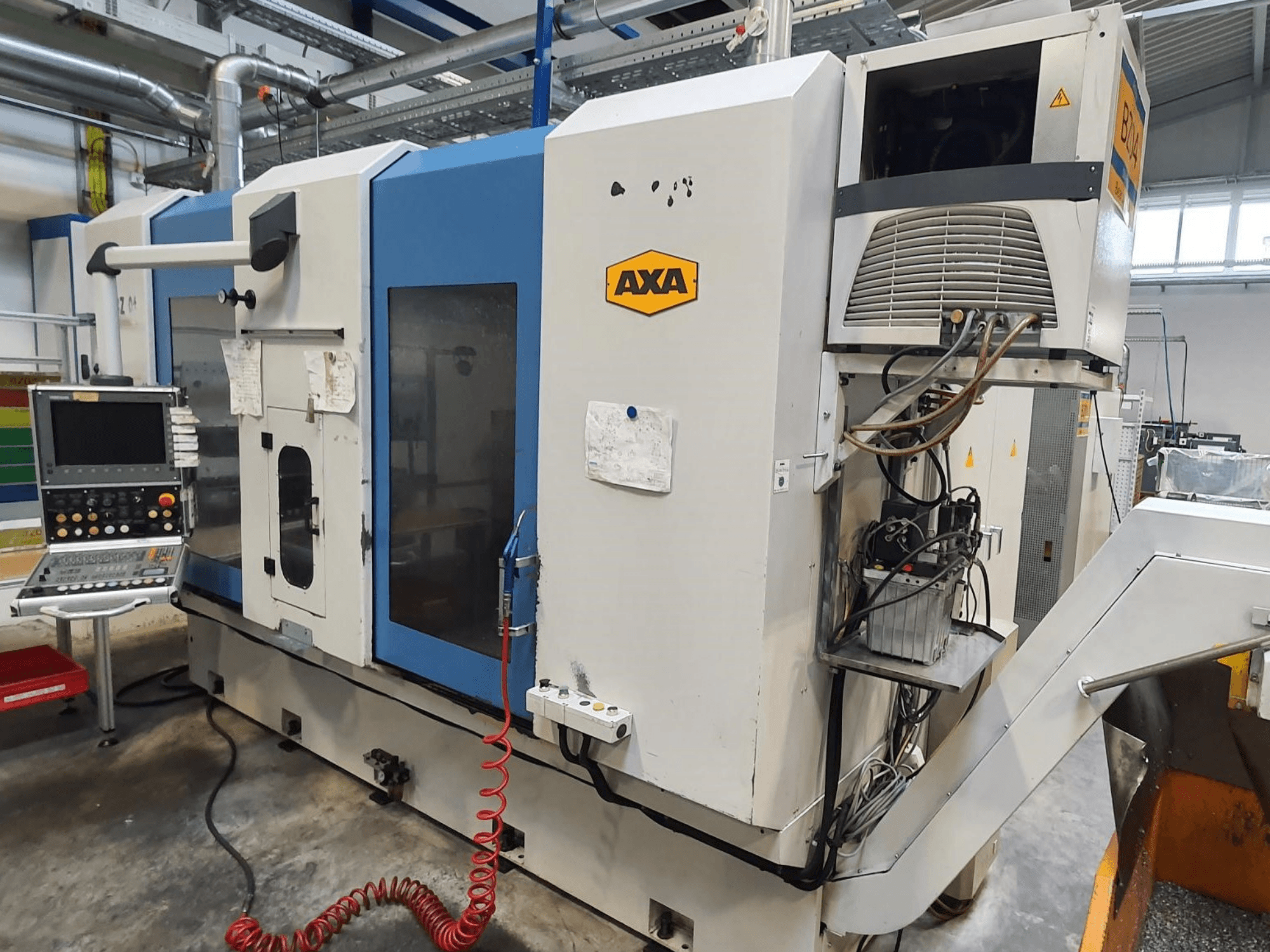 Centro de maquinagem vertical AXA DBZ, vista frontal, com painel de controlo e detalhe visível do sistema de refrigeração.