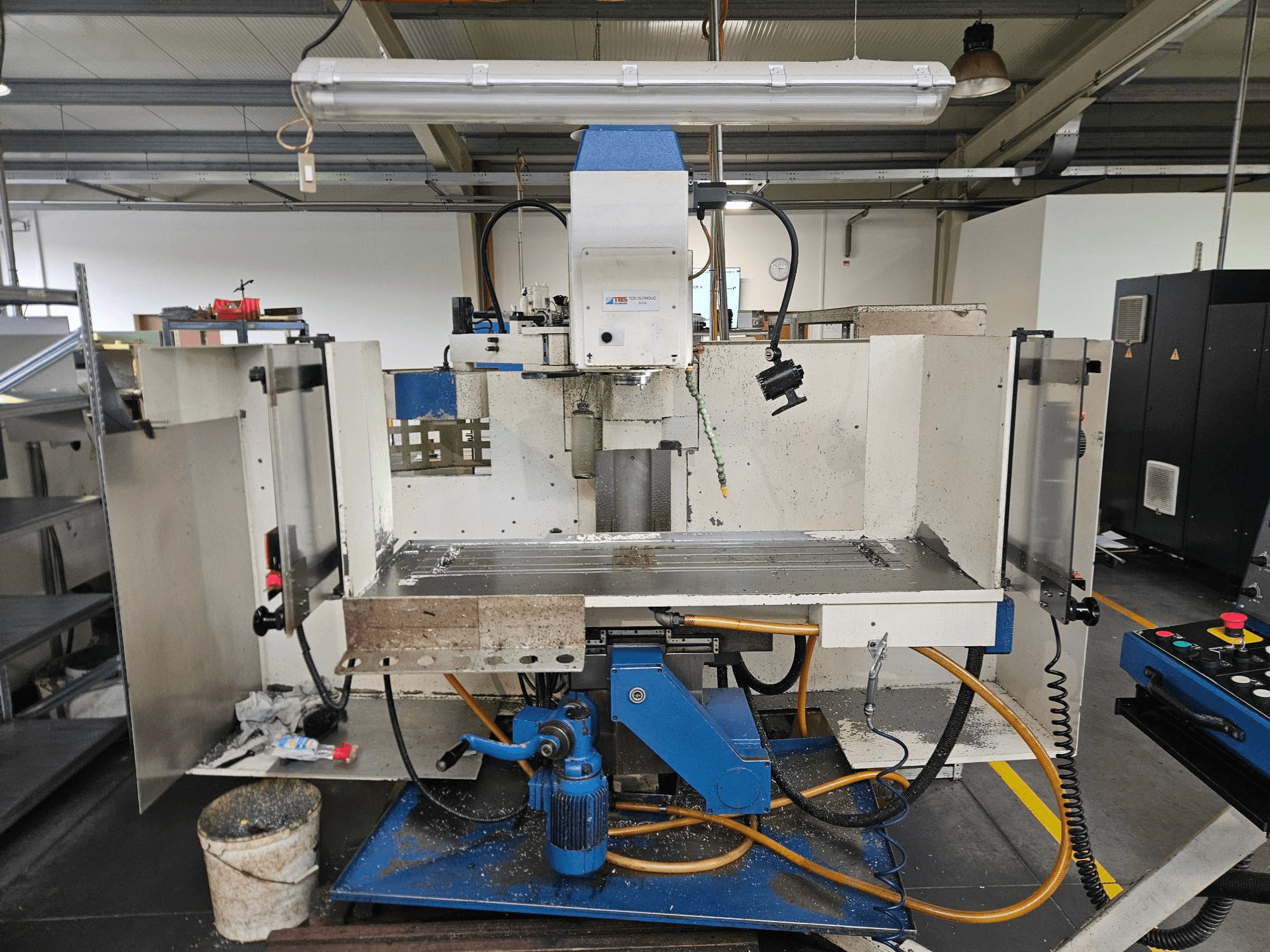 TOS Olomouc FV30 CNC Um centro de maquinação vertical numa oficina, vista frontal mostrando o painel de controlo, a mesa de trabalho e o sistema de refrigeração.