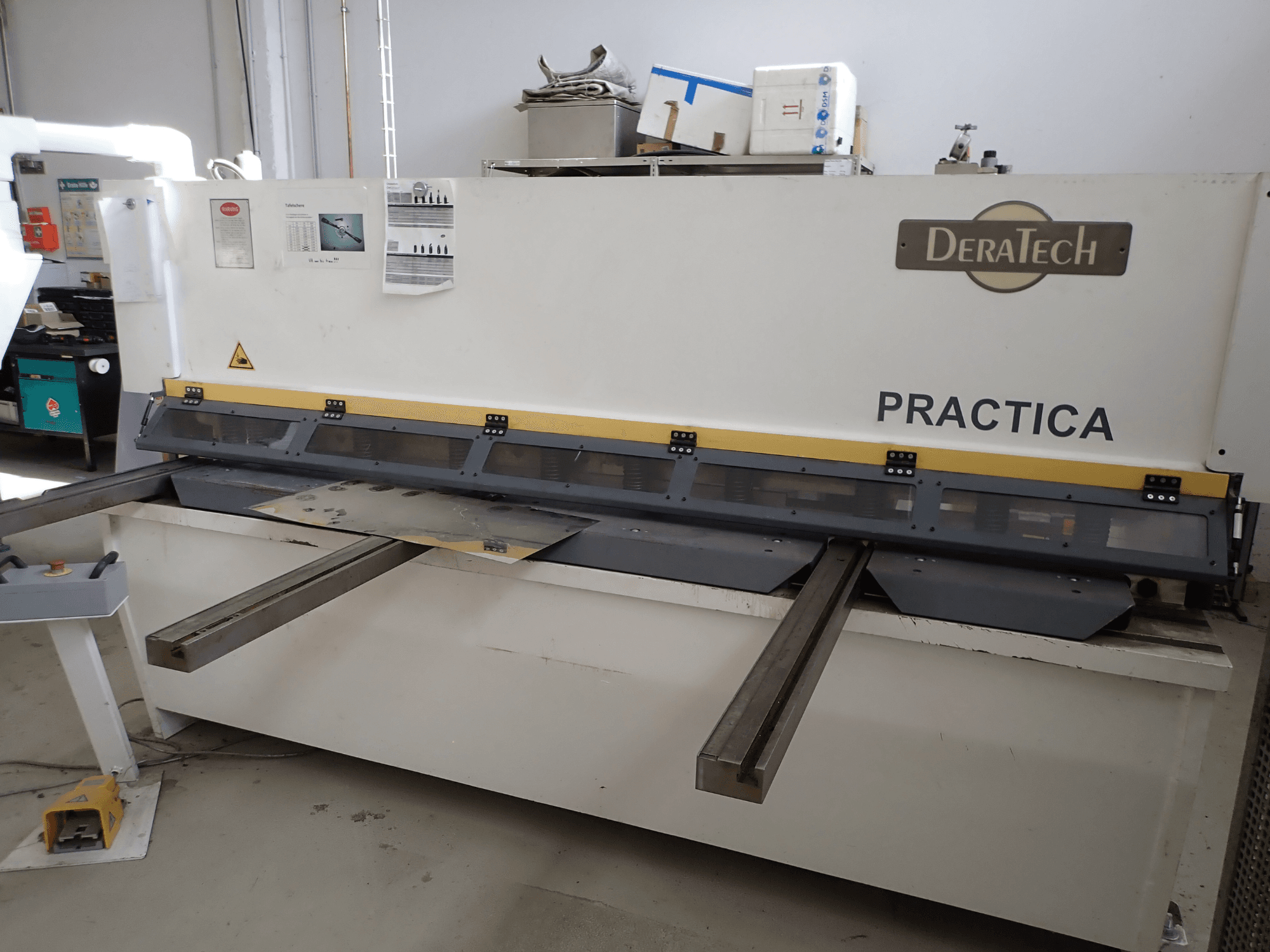 Máquina de corte CNC DERATECH Practica, vista frontal, mostrando o disco de corte e as chapas metálicas na superfície de trabalho.