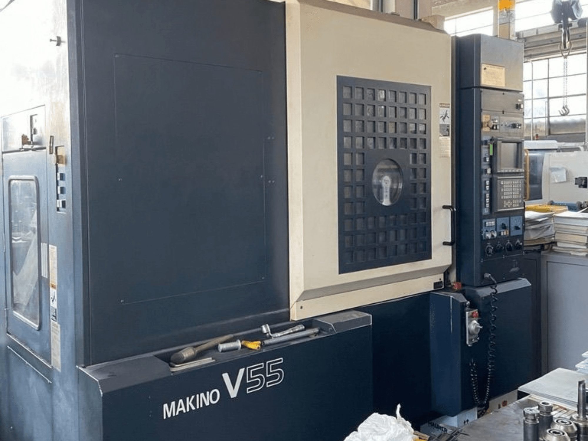 Centro de maquinagem vertical Makino V55-A15, vista frontal que mostra o painel de controlo, a construção robusta e a configuração da área de trabalho.