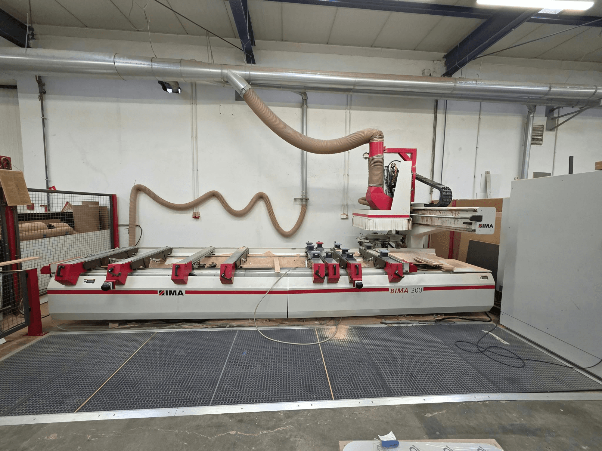Centro de usinagem de madeira CNC IMA BIMA 300, vista frontal, equipado com uma ferramenta multieixos e um sistema de extração de poeira.