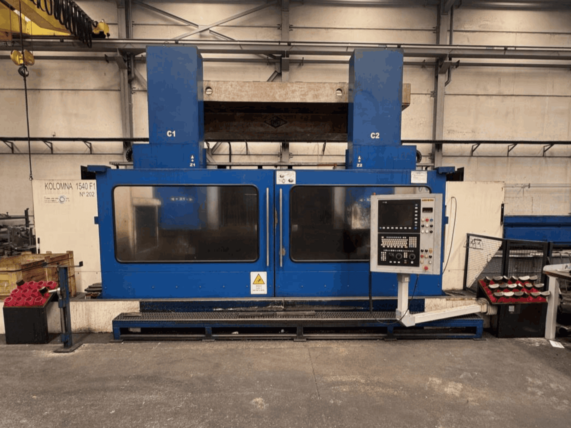Torno vertical KOLOMNA 1540 F1, na cor azul, com painel de controlo, visto de frente, mostrando a ampla área de trabalho.