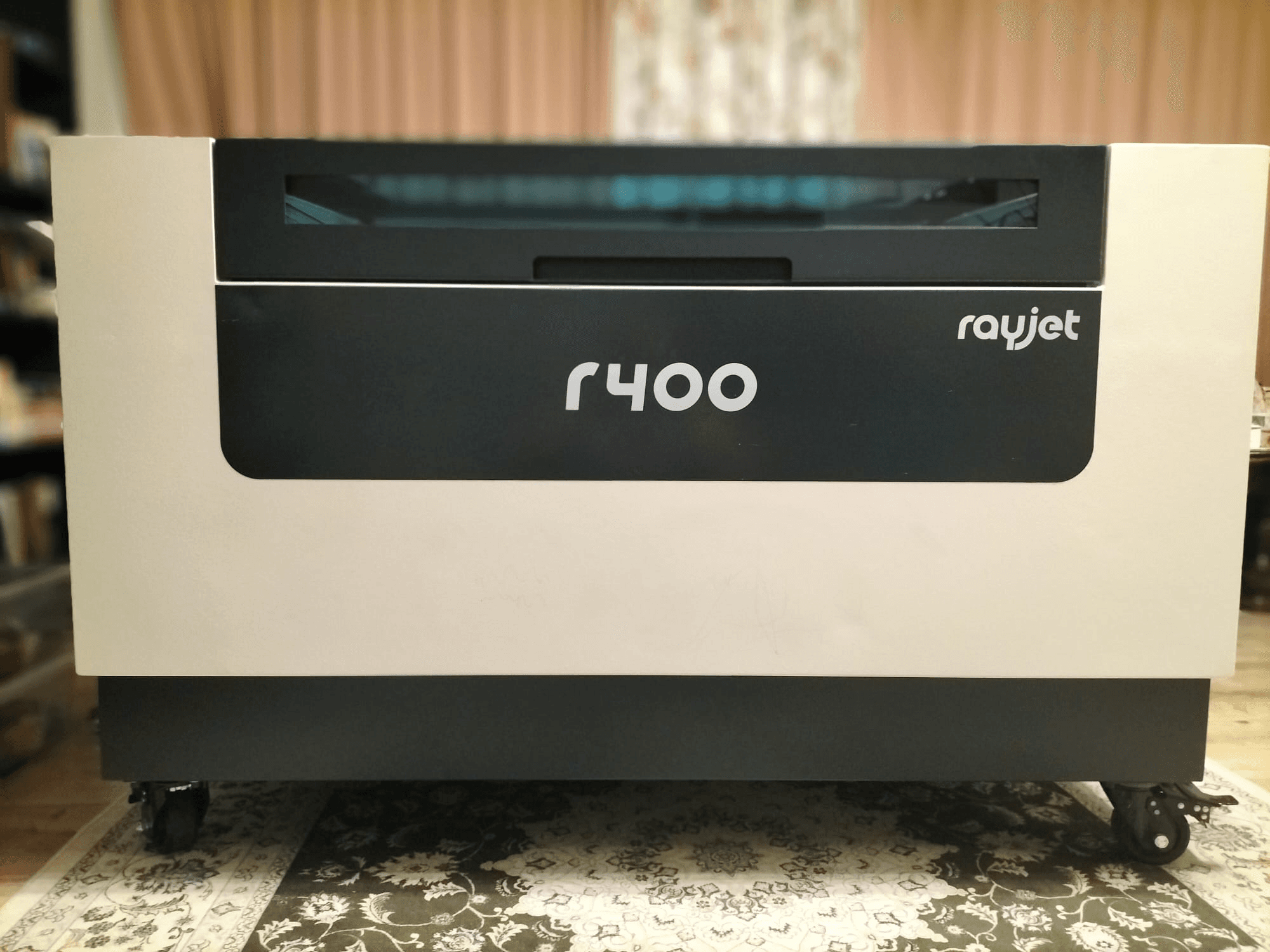 Vista frontal da máquina de gravação a laser Rayjet R400 da Trotec, mostrando o seu design elegante e a sua marca clara.