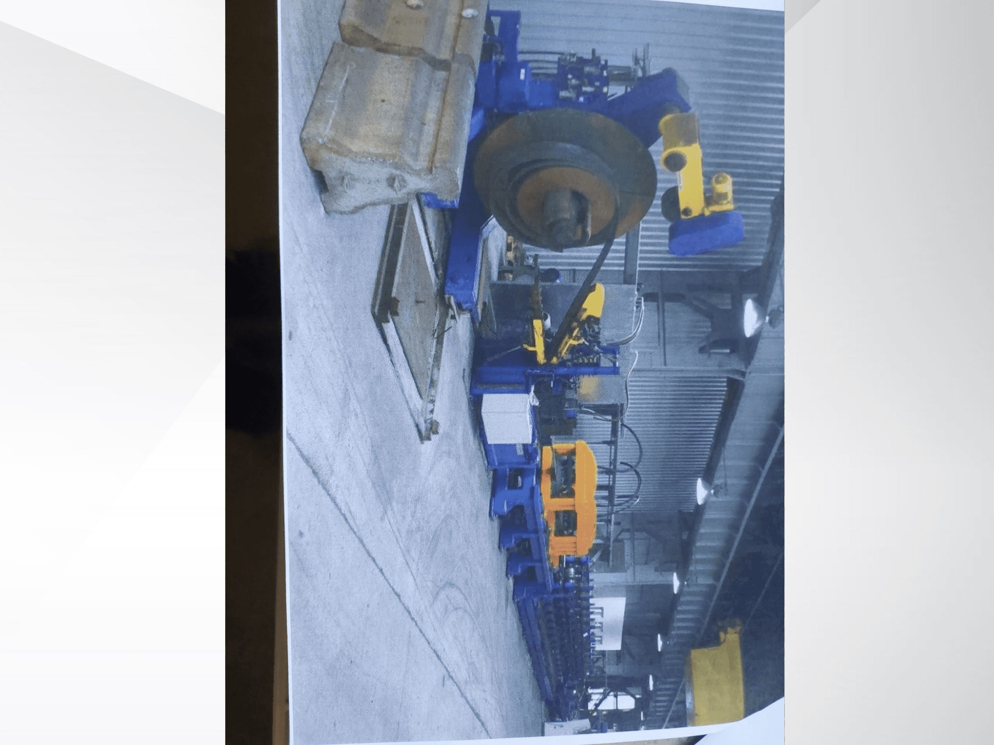 Máquina de dobragem de perfis Müller Profilierung 3 numa oficina, com a estrutura azul e os componentes hidráulicos amarelos em destaque.