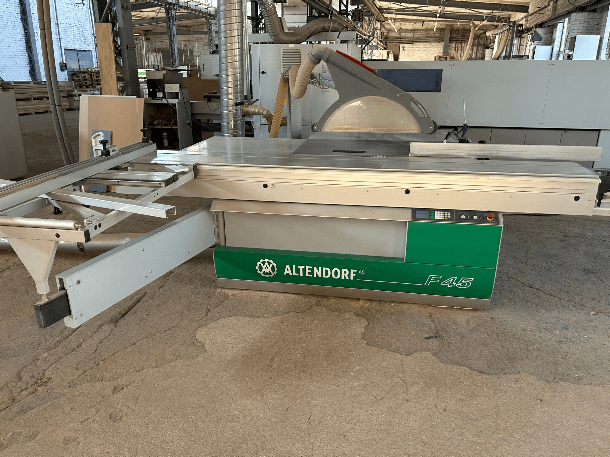 Serra de painéis Altendorf F 45, vista frontal, mostrando a mesa de corte, a proteção da lâmina e o painel de controlo na máquina verde e cinzenta.