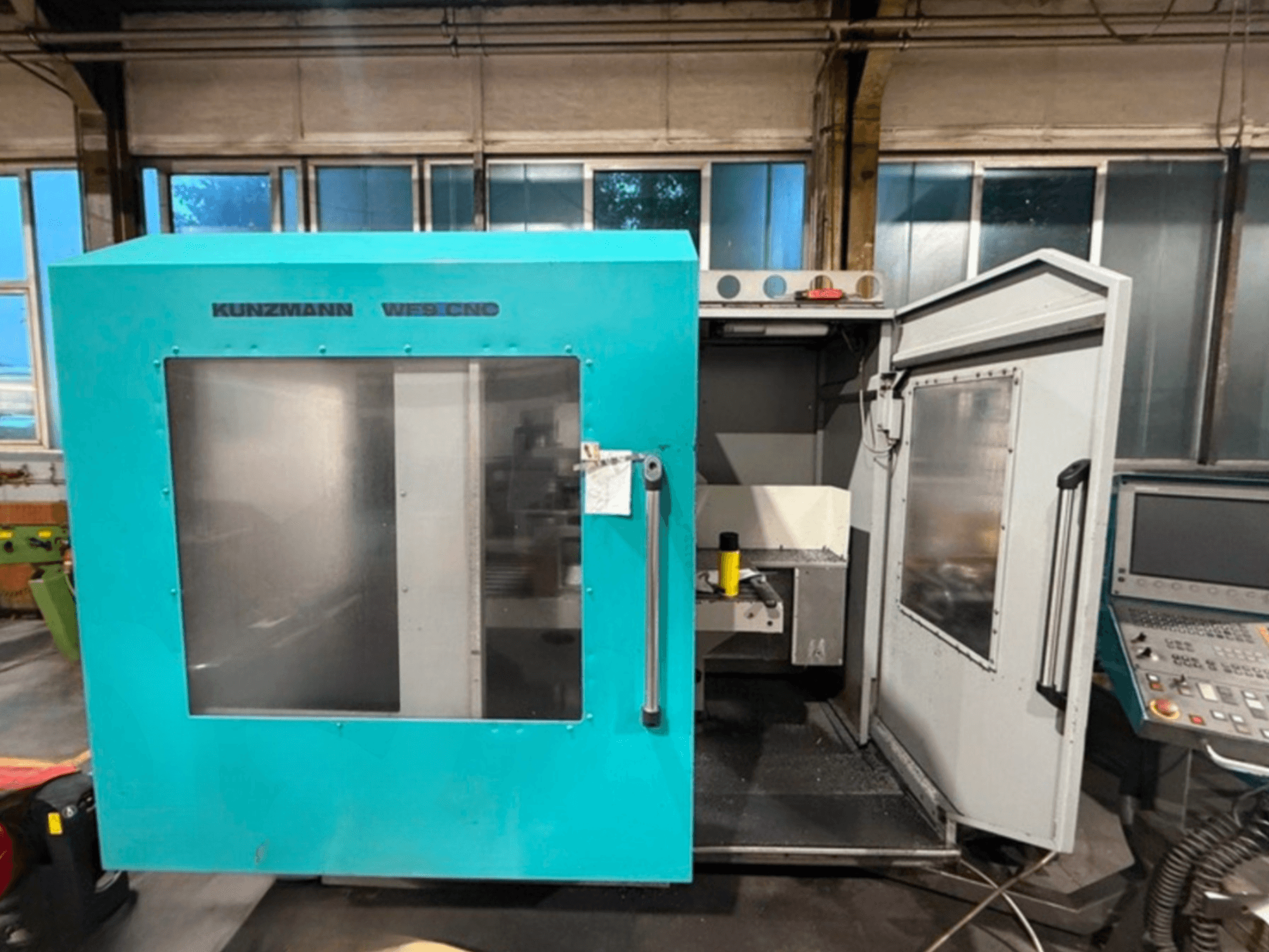 Centro de maquinação vertical CNC KUNZMANN WF9, vista frontal com portas abertas, mostrando o interior e o painel de controlo.