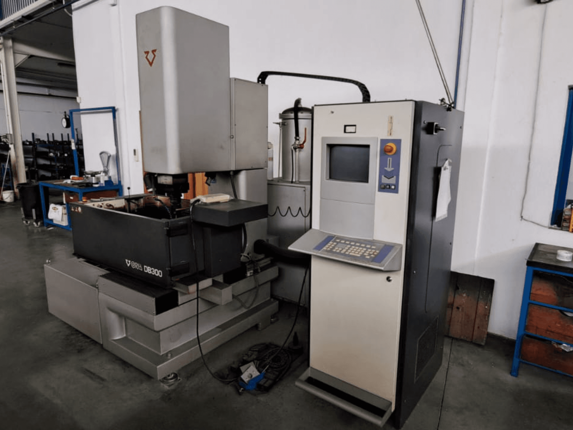 Máquina de electroerosão por penetração ONA DB300, vista frontal; com painel de controlo, suporte da peça de trabalho e elementos de design industrial.