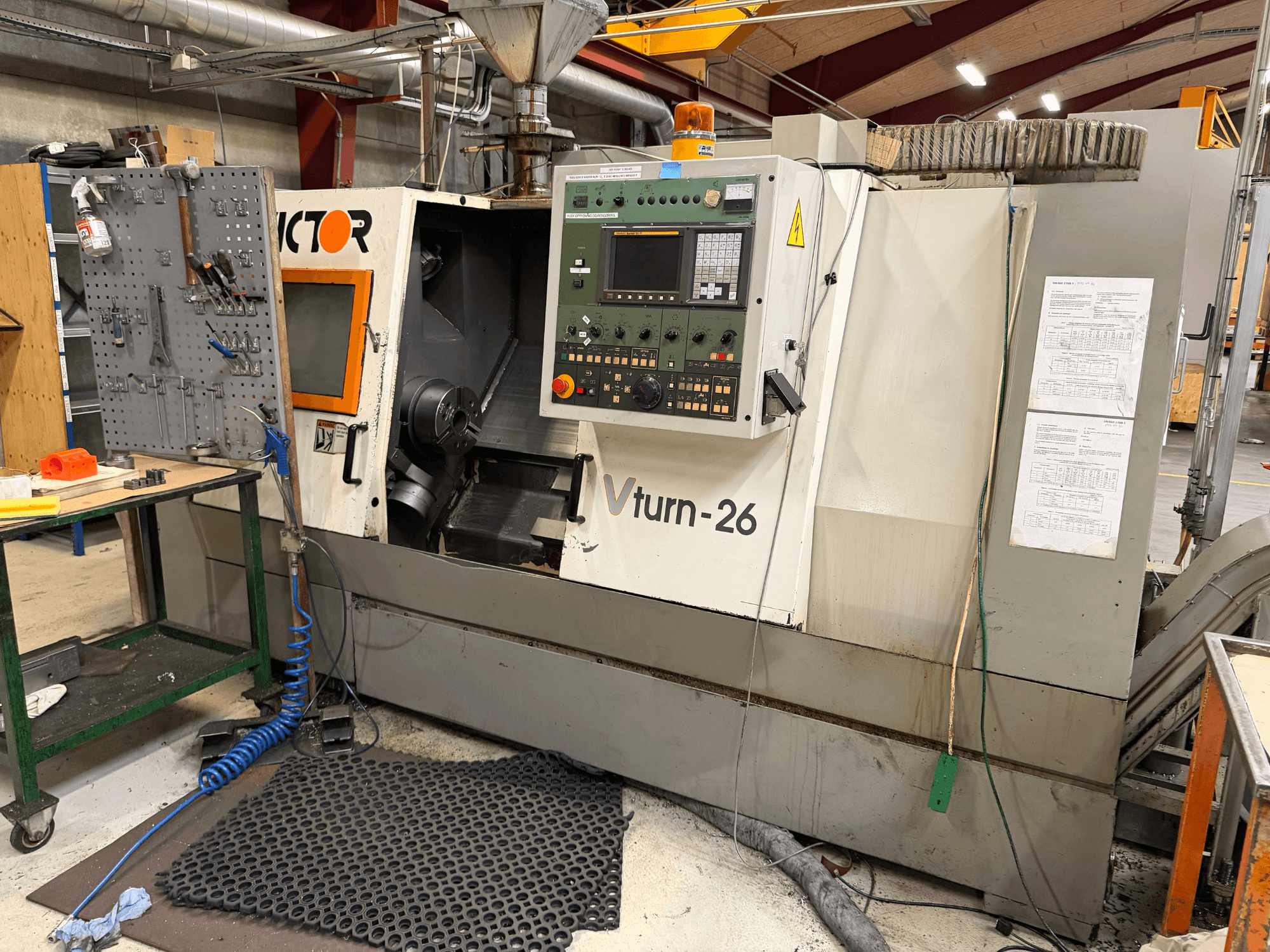 A máquina de torneamento horizontal Victor VTurn-26, vista frontal, mostra o painel de controlo e os componentes operacionais num ambiente de oficina.