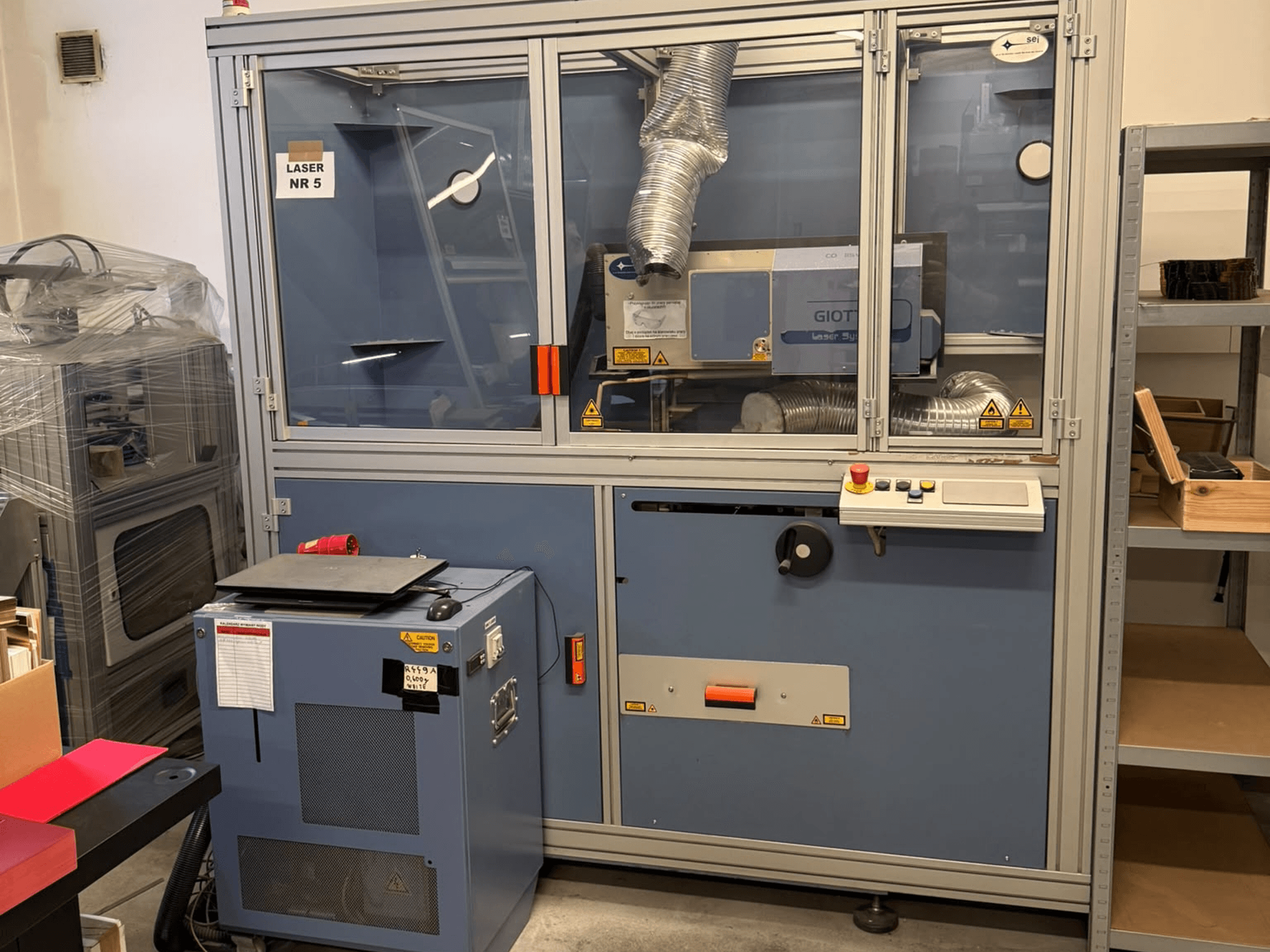 Máquina de corte a laser de CO₂ da SEI Laser, modelo PAPER BLASTER 02, vista de frente com o painel de controlo e o sistema de ventilação.