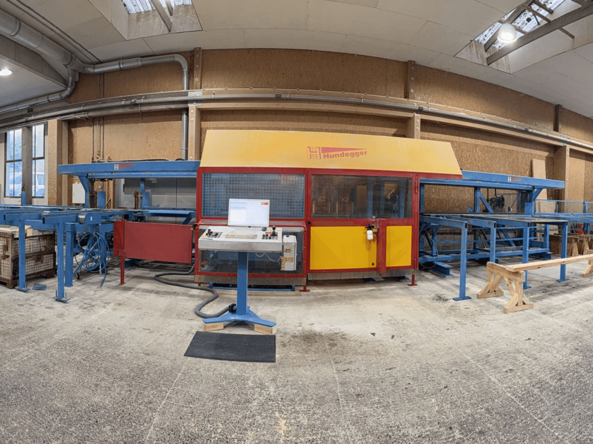 Vista frontal da linha completa de produção de madeira HUNDEGGER K2-4-450, com painel de controlo e sistema de transporte.