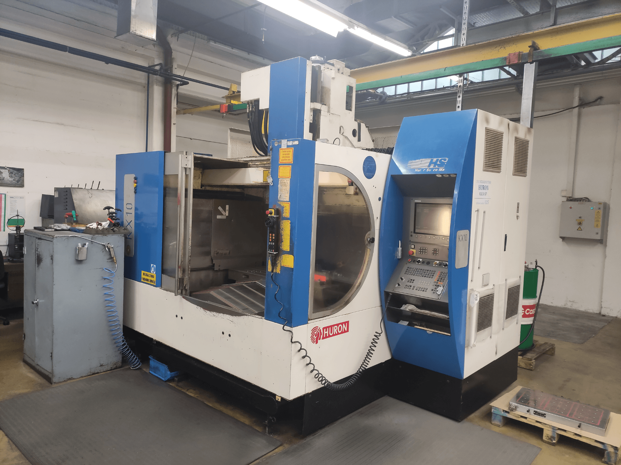 Máquina CNC HURON KX10 numa oficina, vista frontal, com painel de controlo e grande abertura para maquinagem.