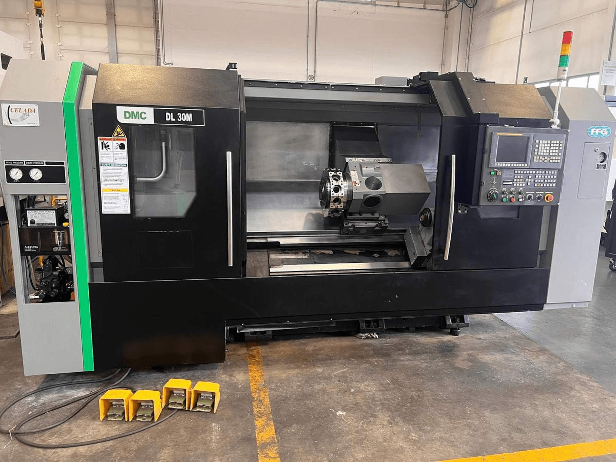 Máquina CNC DMC DL 30M com uma vista lateral que mostra os controlos, o fuso e três pedais no chão.