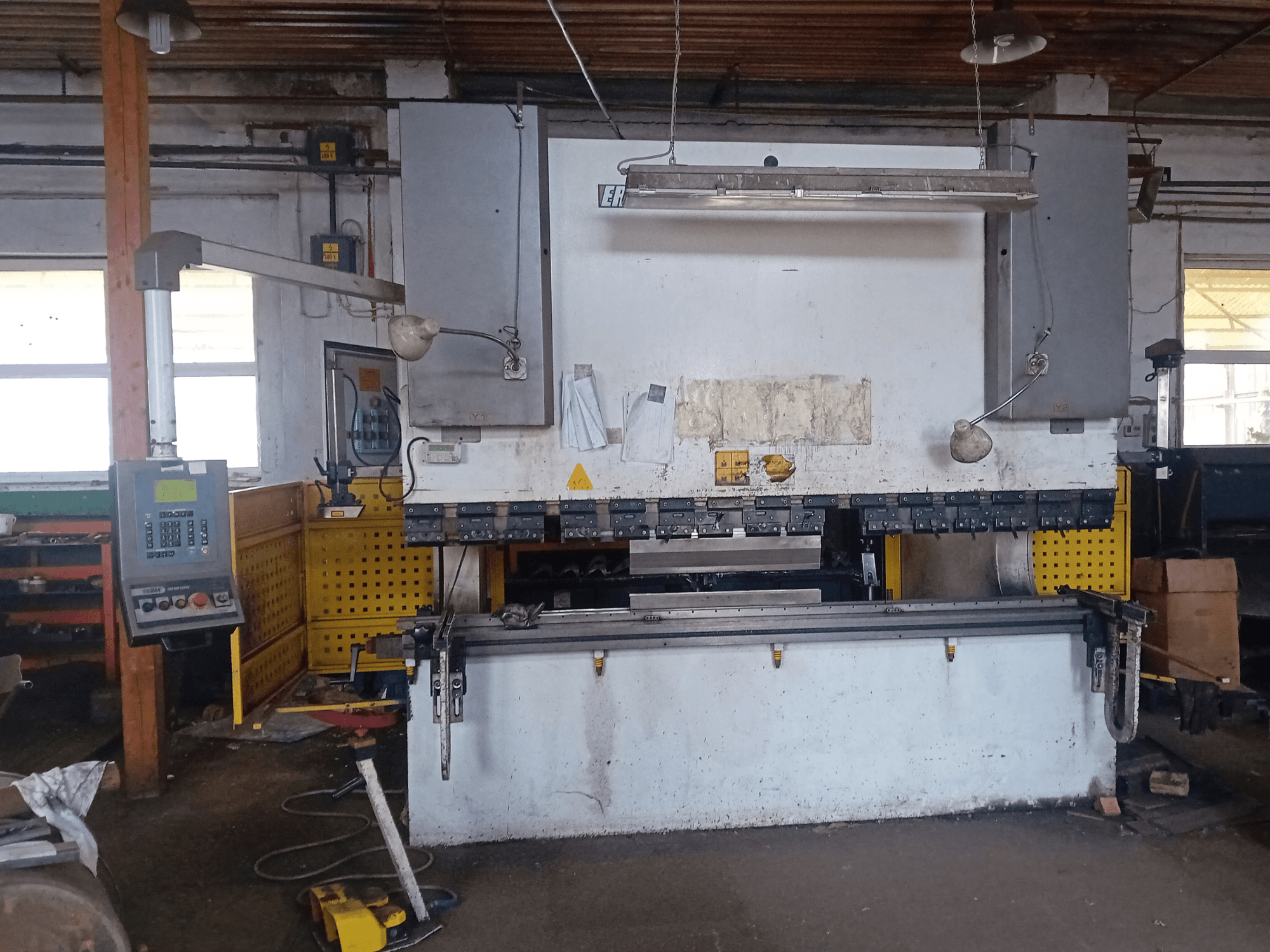 Prensa hidráulica ERMAK CNC HAP 3100x300 mostrada em vista frontal, com painel de controlo e bancada de trabalho num ambiente de oficina.