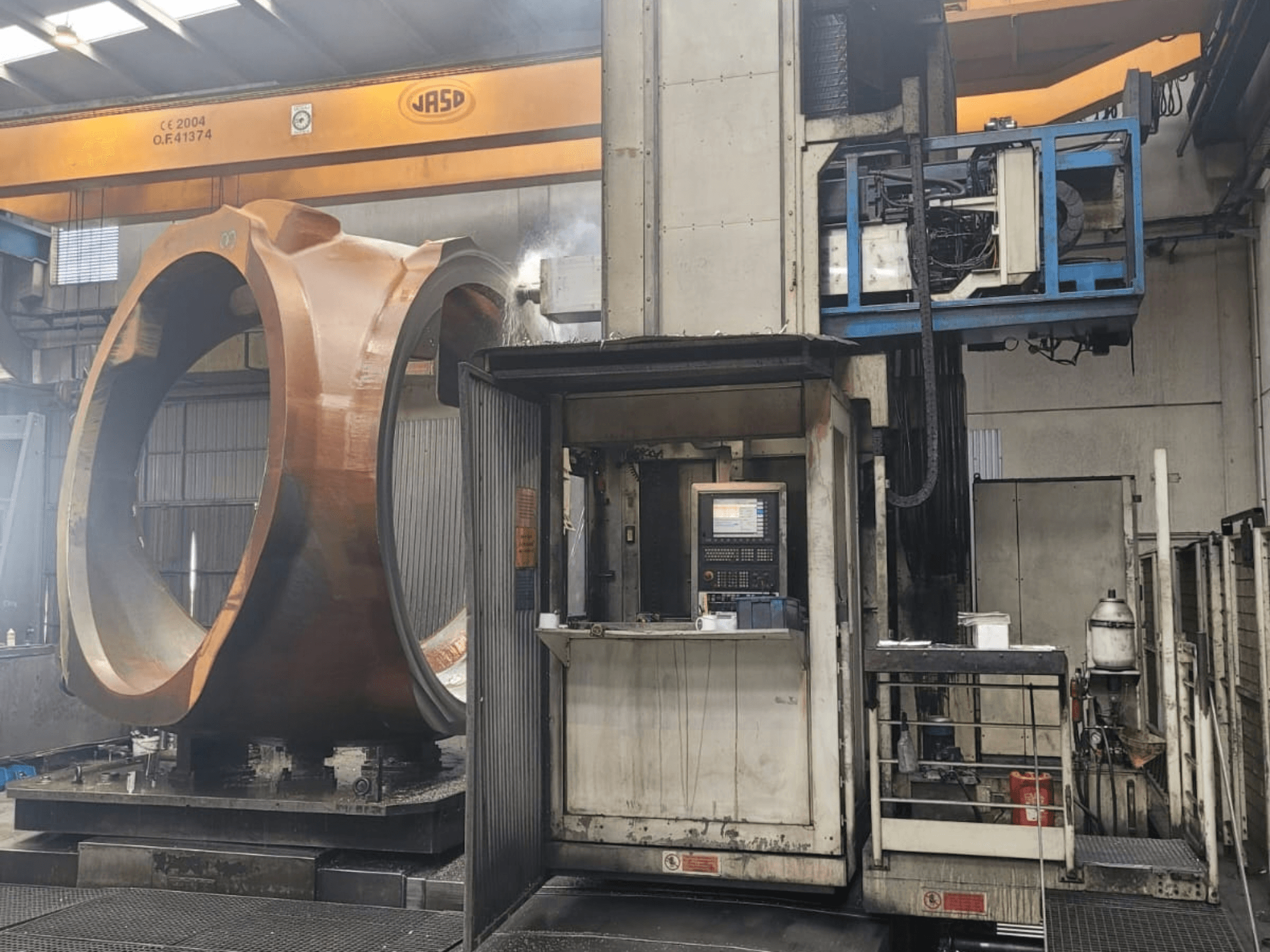 Centro de fresagem e torneamento PAMA Speedram 1000, vista lateral, mostrando uma peça de grandes dimensões e o painel de controlo num ambiente industrial.