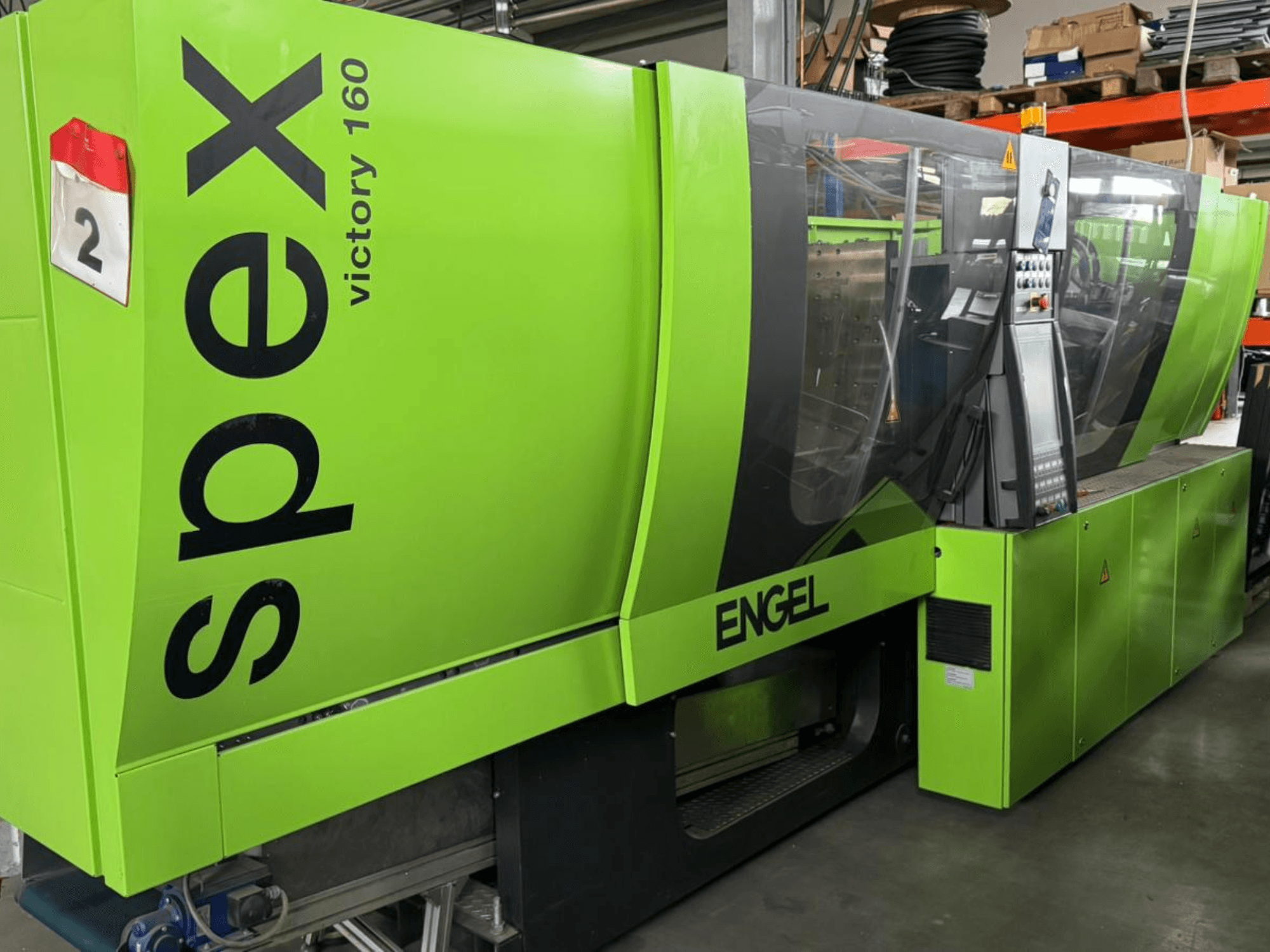 Máquina Engel Victory 160 verde, vista de frente, com o painel de controlo e os avisos de segurança visíveis, apresentando um design industrial.
