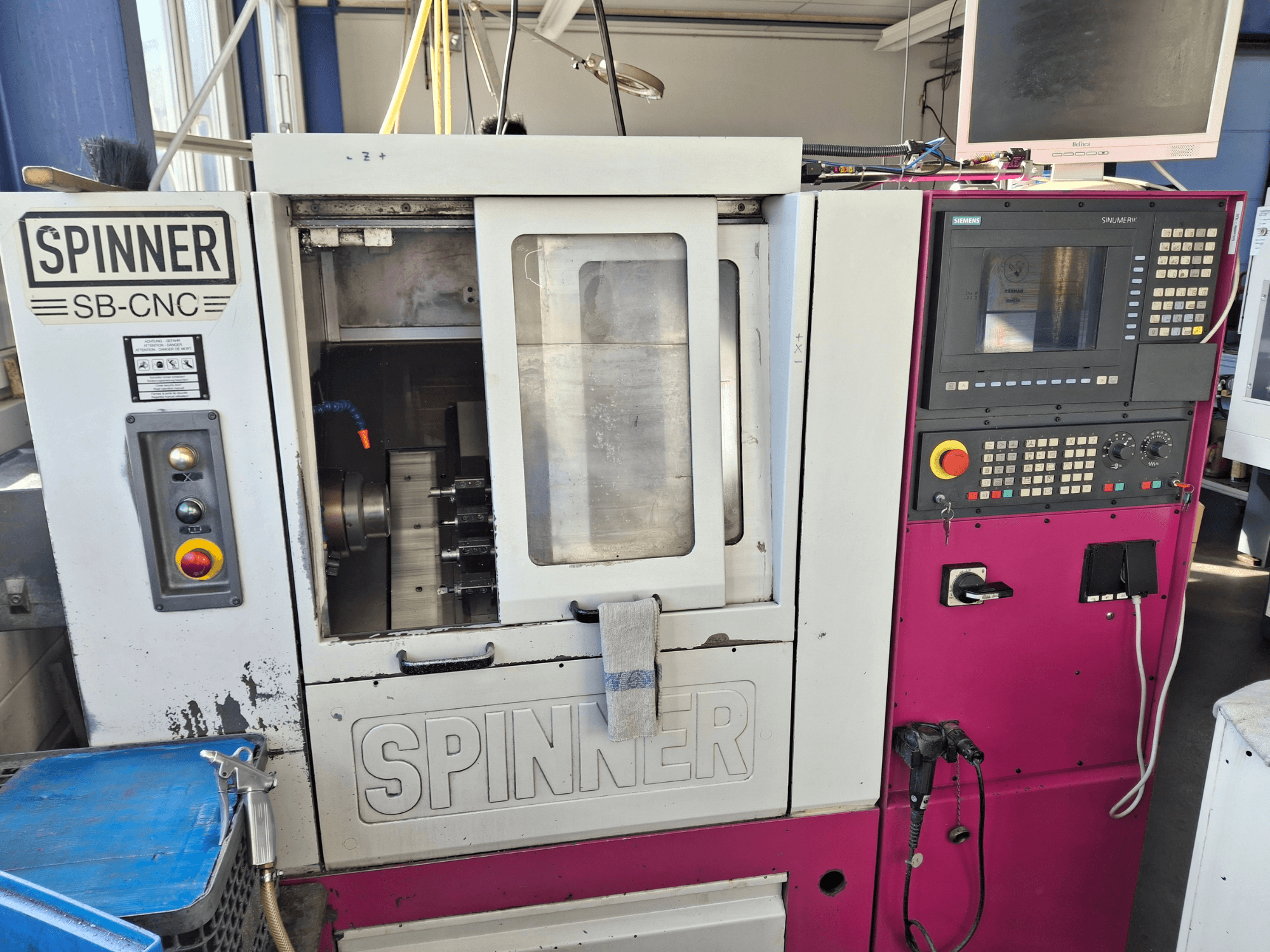 Máquina de torneamento horizontal SPINNER SB-CNC, vista frontal mostrando o painel de controlo, suporte da ferramenta e indicadores operacionais.