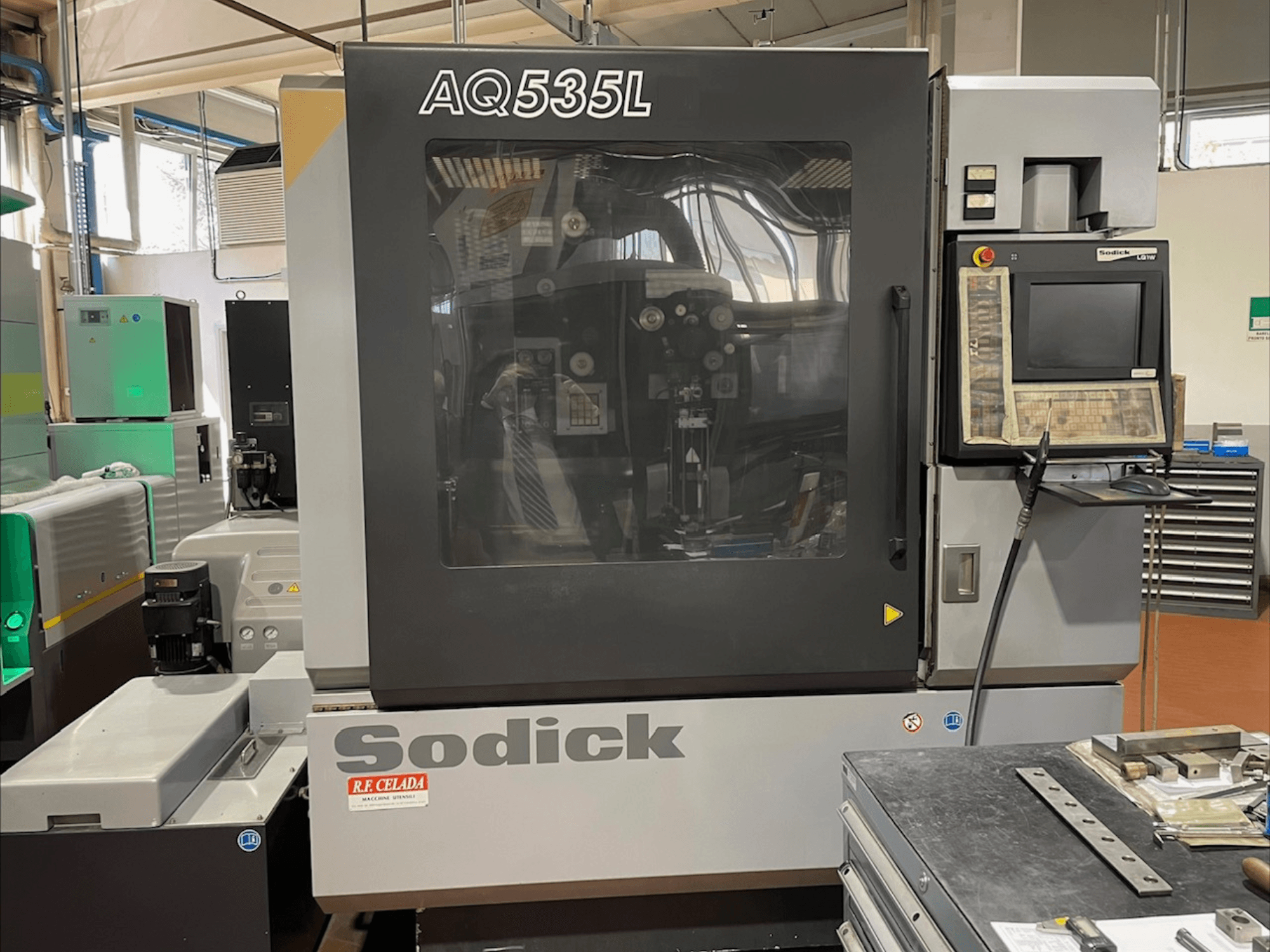 Vista frontal da máquina EDM de fio Sodick AQ535L, com painel de controlo e tampa de proteção transparente.