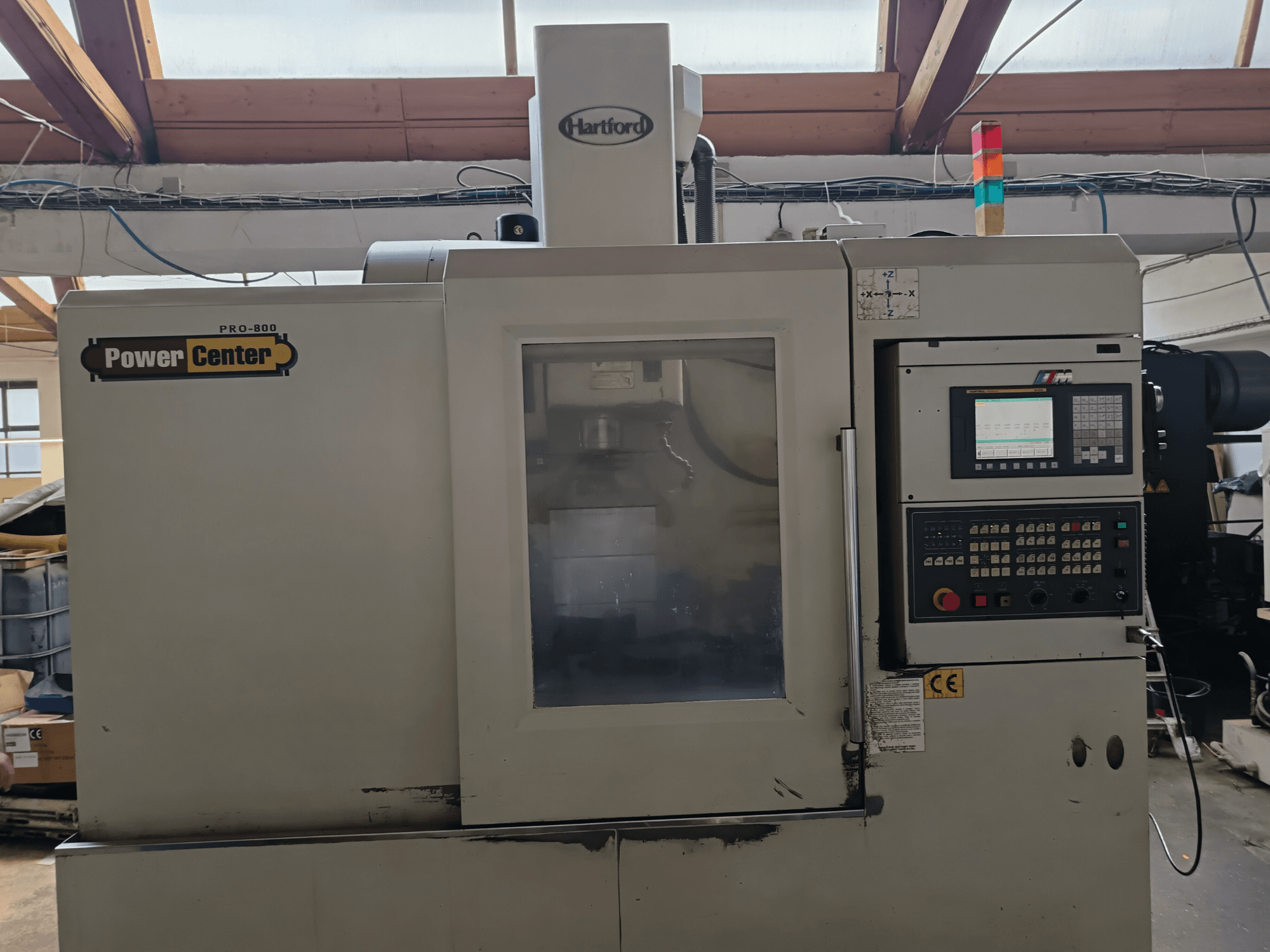 Centro de usinagem vertical HARTFORD PRO-800A, vista frontal, mostrando o painel de controlo e o painel de vidro que permite a visibilidade do interior.