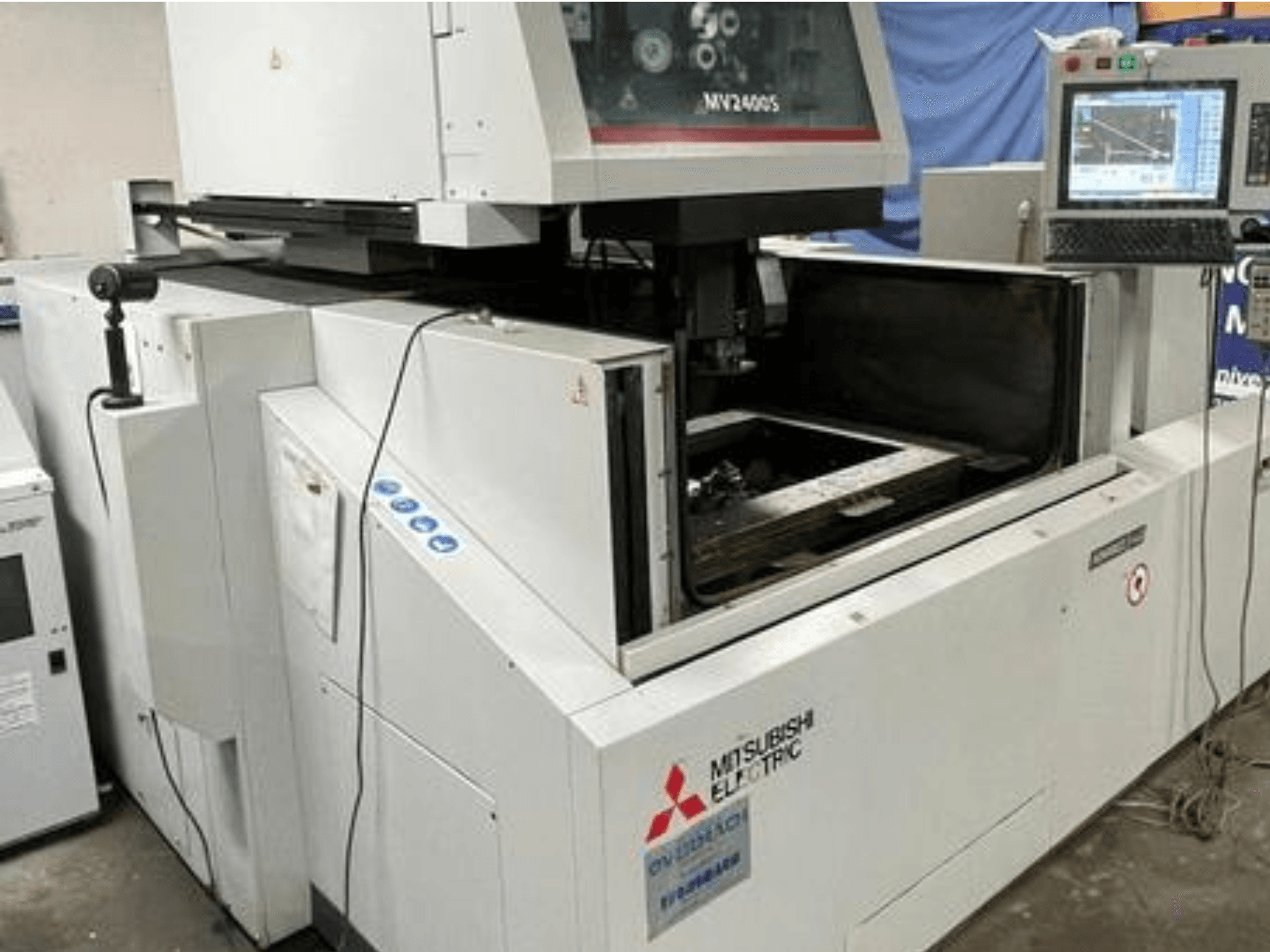 Máquina EDM de corte de fio MV2400S da Mitsubishi Electric, vista frontal, mostrando o painel de controlo e a área de trabalho aberta.