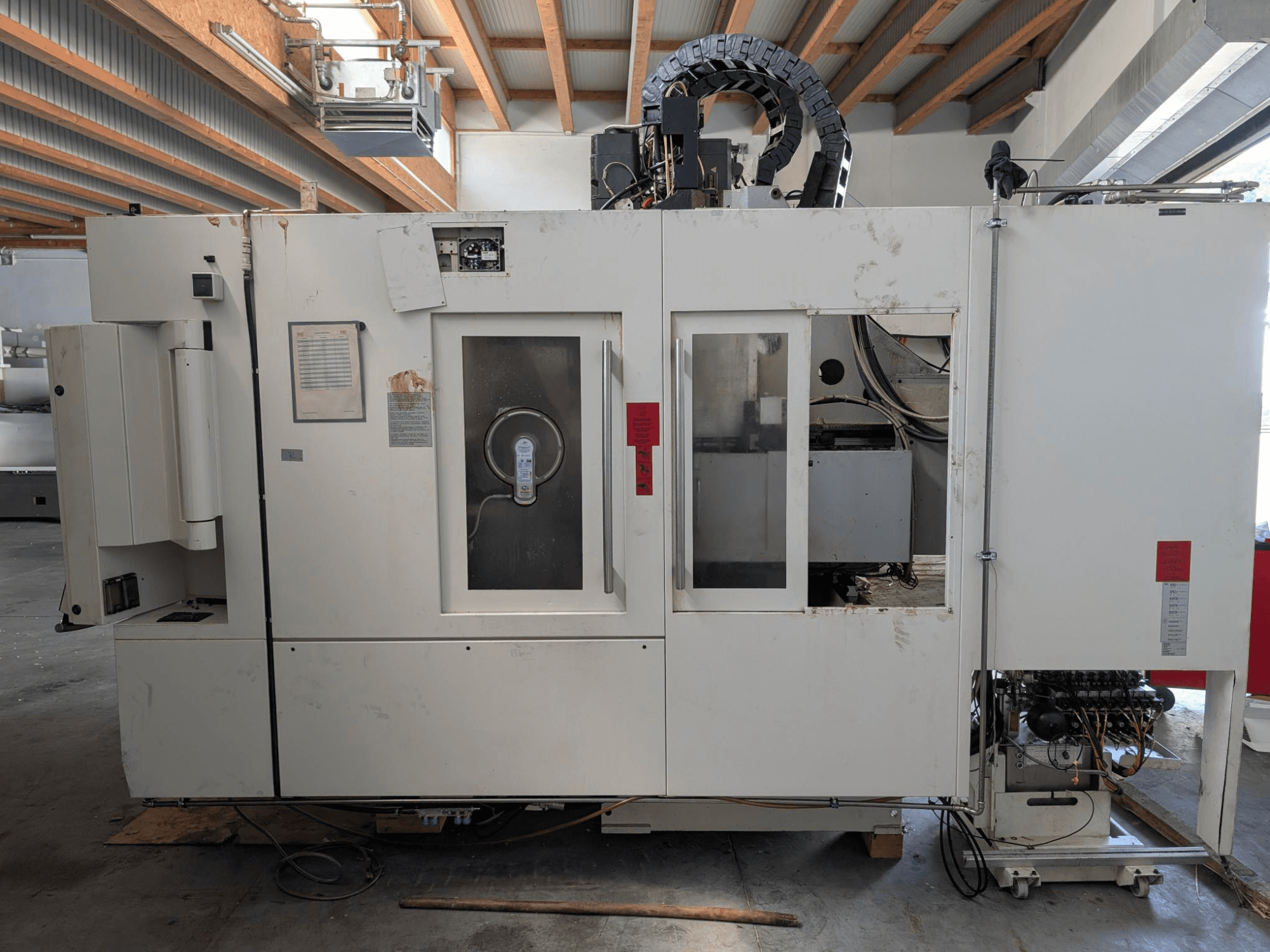 Centro de maquinação vertical STAMA MC 326, vista lateral mostrando o painel de controlo, a área do fuso e várias etiquetas na máquina.