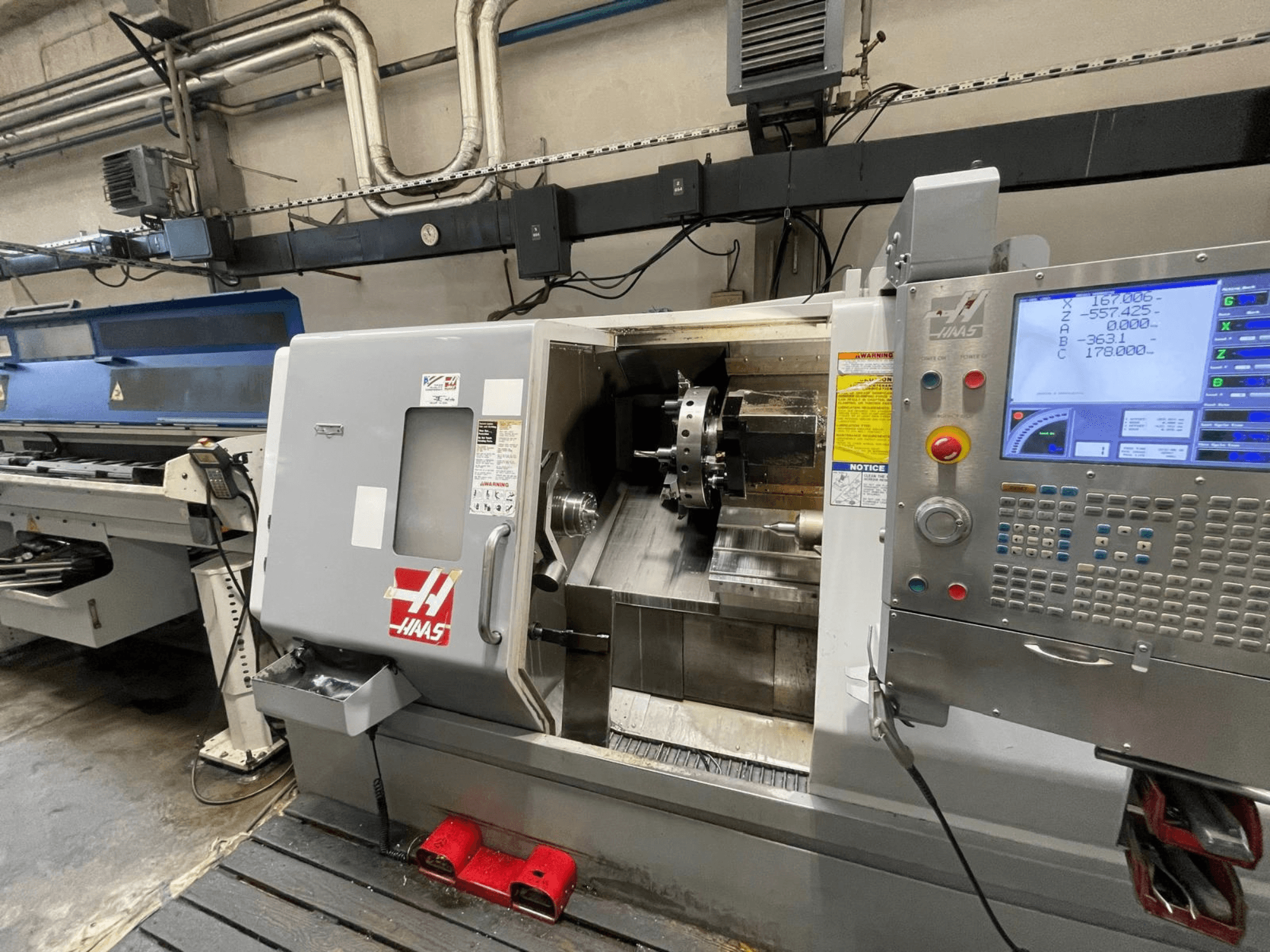 A máquina de torneamento horizontal Haas SL-30THE numa oficina, com um painel de controlo digital e uma área de trabalho exposta.