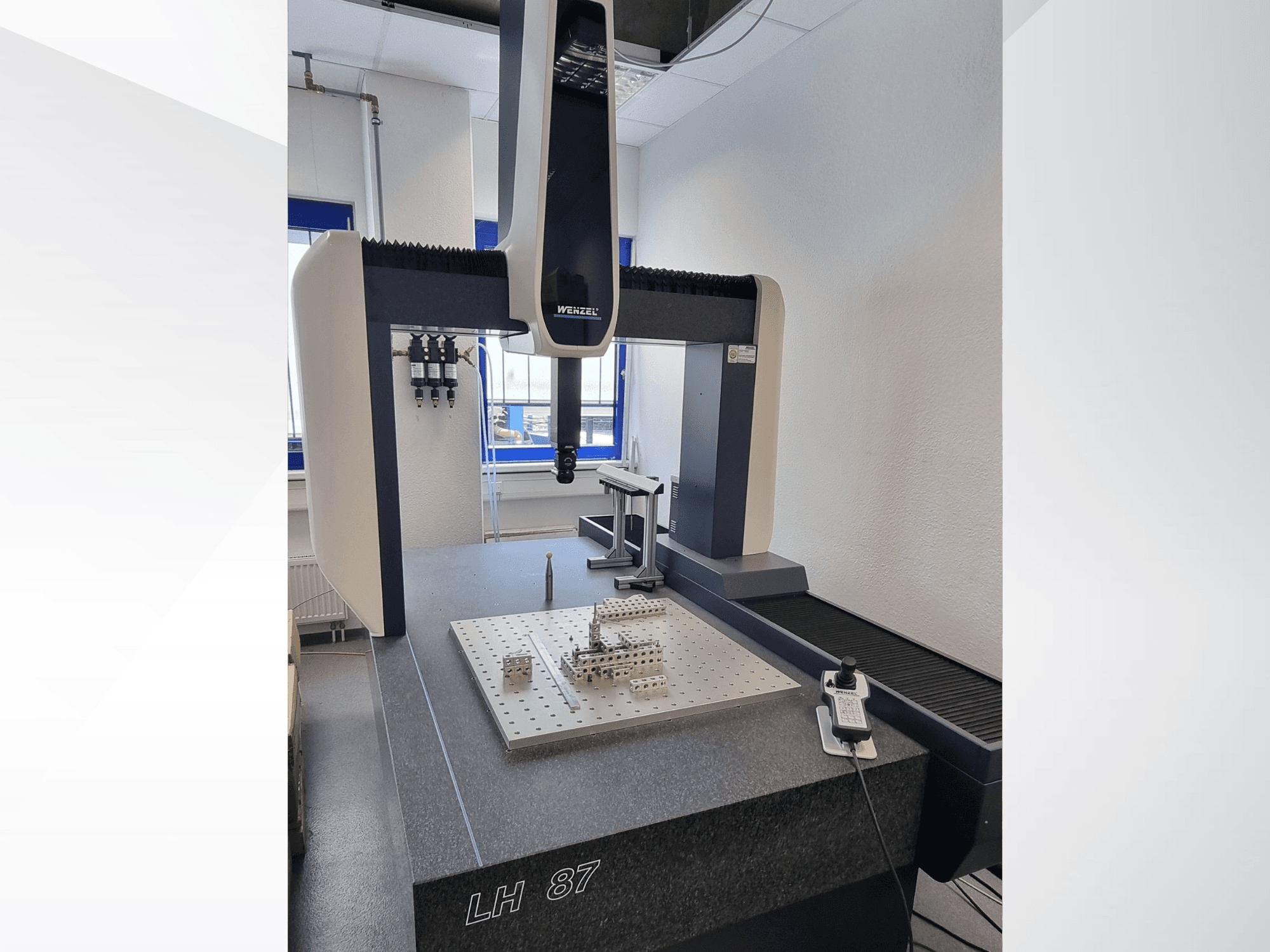 Máquina de medição por coordenadas (CMM) Wenzel LH 87 num laboratório, vista frontal com a sonda de medição posicionada sobre uma placa de precisão e o controlador digital visível.
