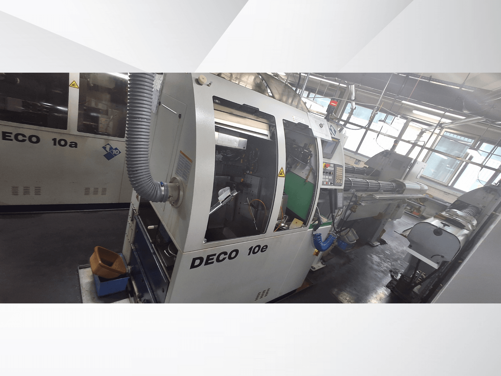 Máquina CNC DECO 10e em vista lateral, com painel de controlo, interior verde e tubo de escape ligado.