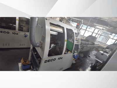 Máquina CNC DECO 10e em vista lateral, com painel de controlo, interior verde e tubo de escape ligado.