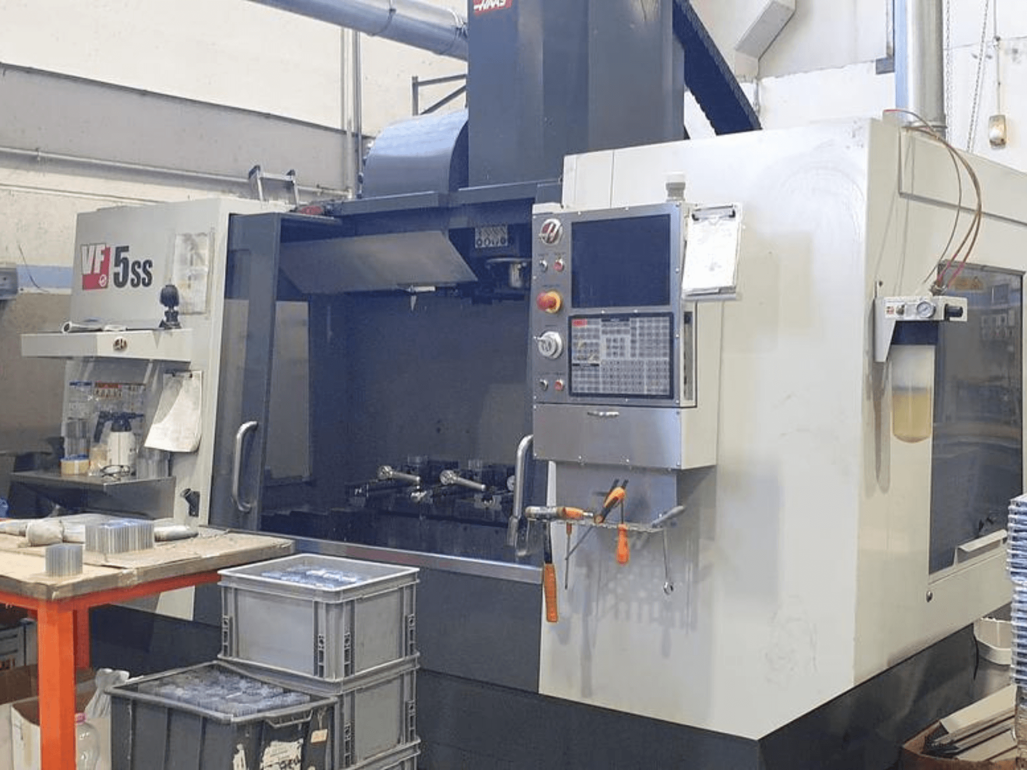 Centro de maquinação vertical HAAS VF-5SS em vista frontal, mostrando o painel de controlo, a área de trabalho e os compartimentos de armazenamento.
