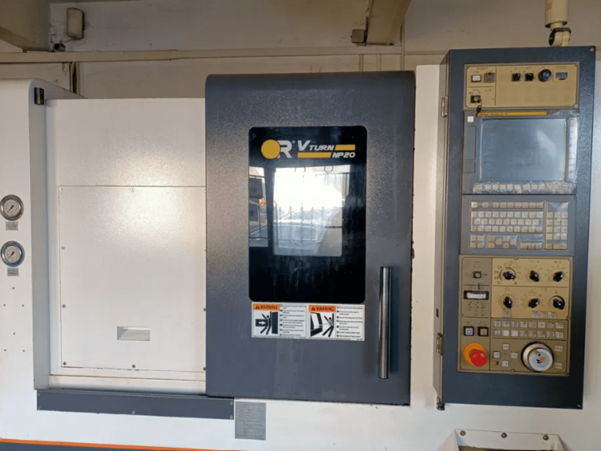 Vista frontal da máquina CNC OR VTURN NP20, com painel de controlo com botões, visor e manómetros na lateral.