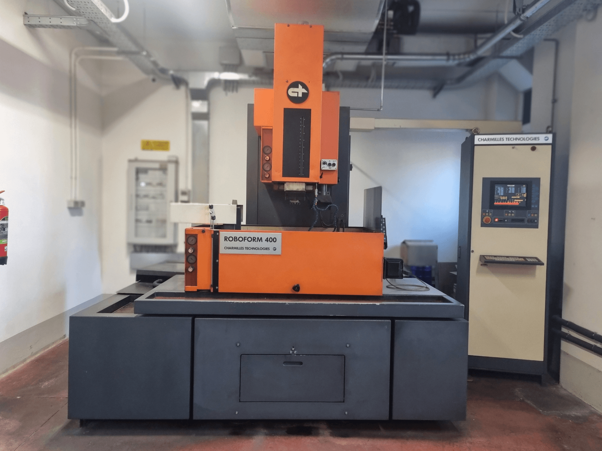 Máquina Roboforn 400 da Charmilles Technologies, vista frontal, com um design laranja e cinzento, painel de controlo digital visível.