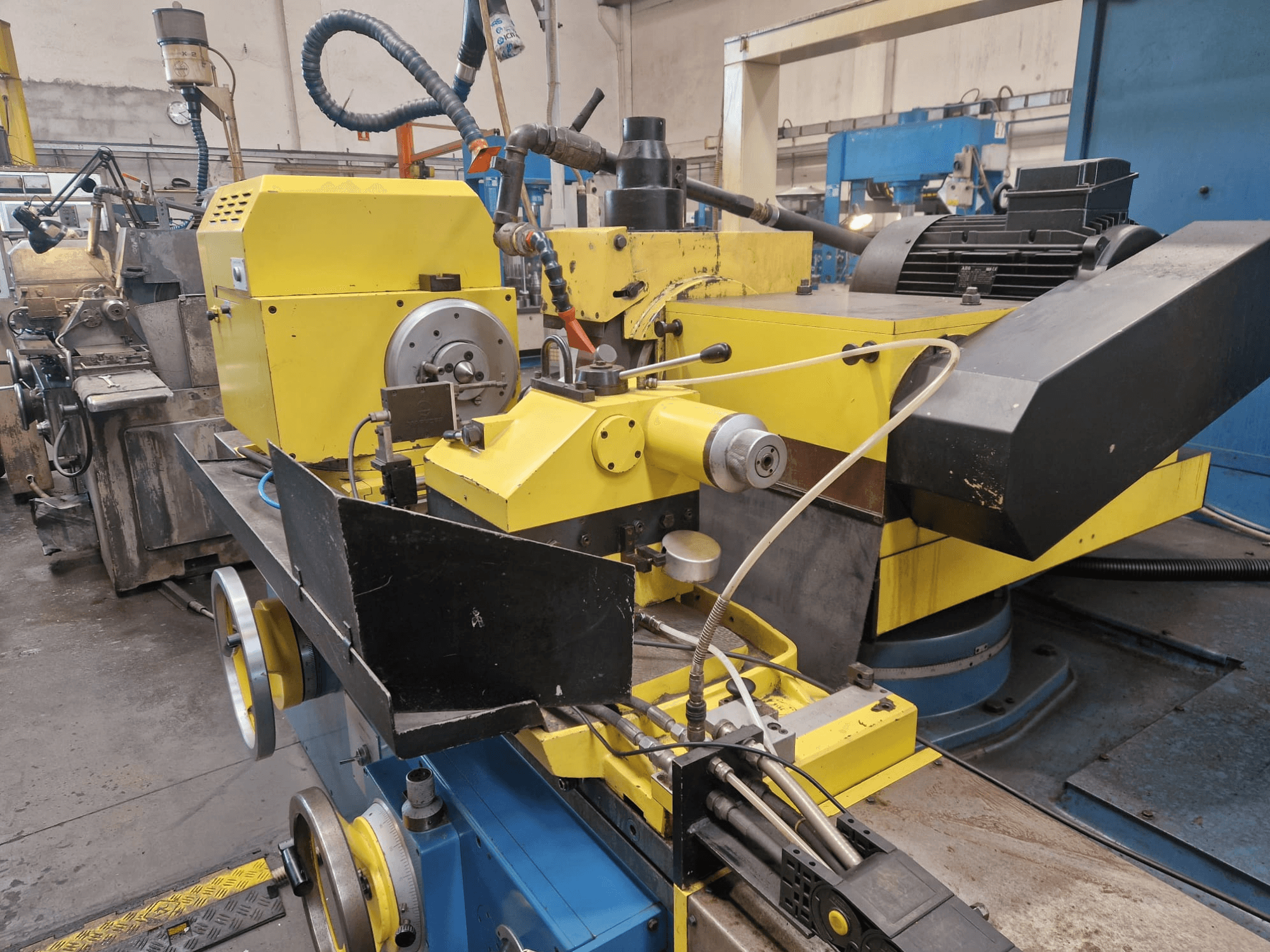 Máquina industrial amarela com uma secção preta, com um mostrador e mangueiras, vista de frente com um ligeiro ângulo.